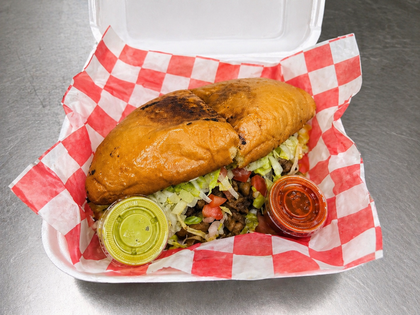 Steak, torta with beans, meat, lettuce, tomato, onions, queso fresco, sour cream, guacamole, jalapeños, and mayo