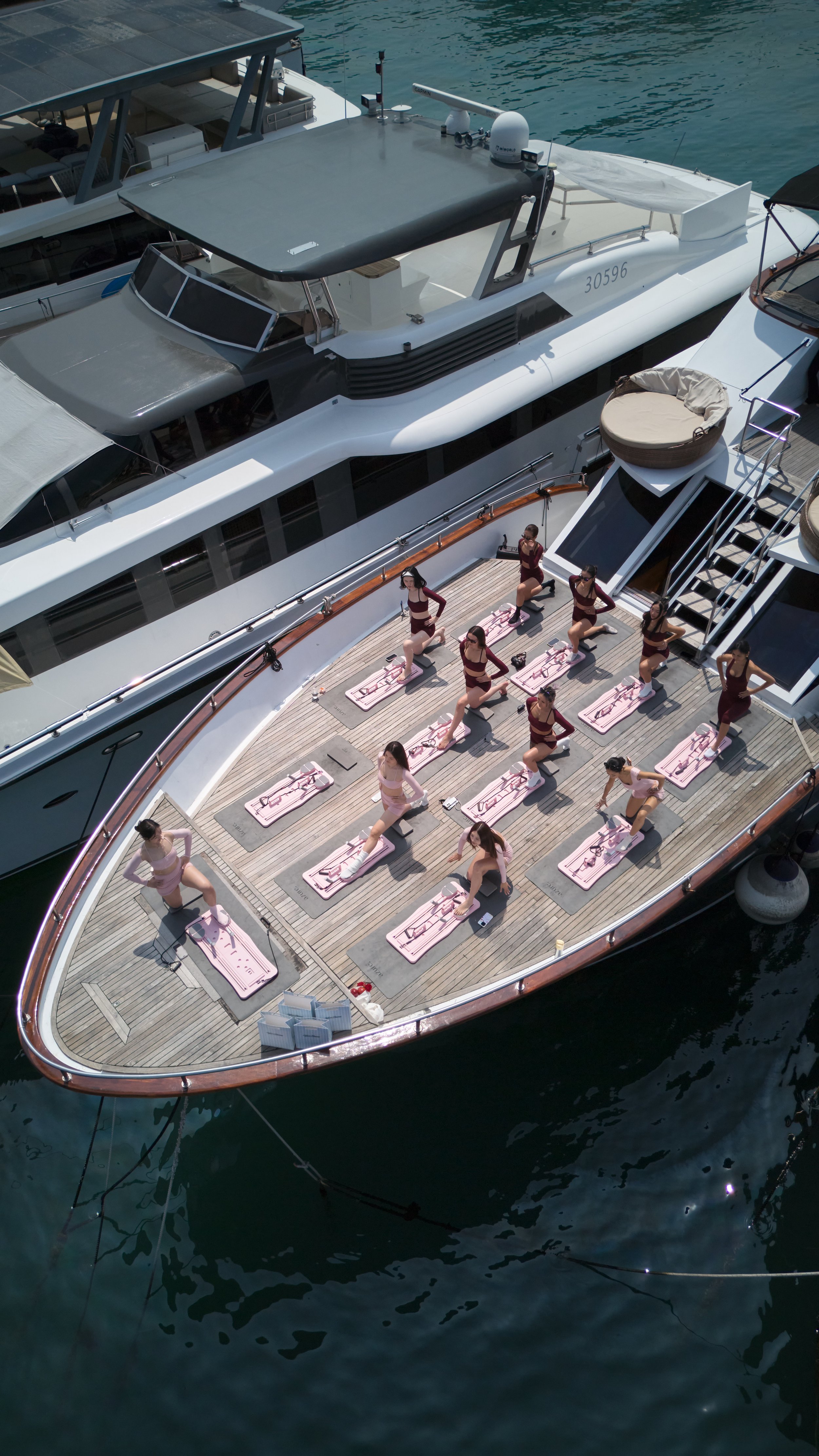 Group of women practicing yoga on yoga mats on the deck of a yacht.