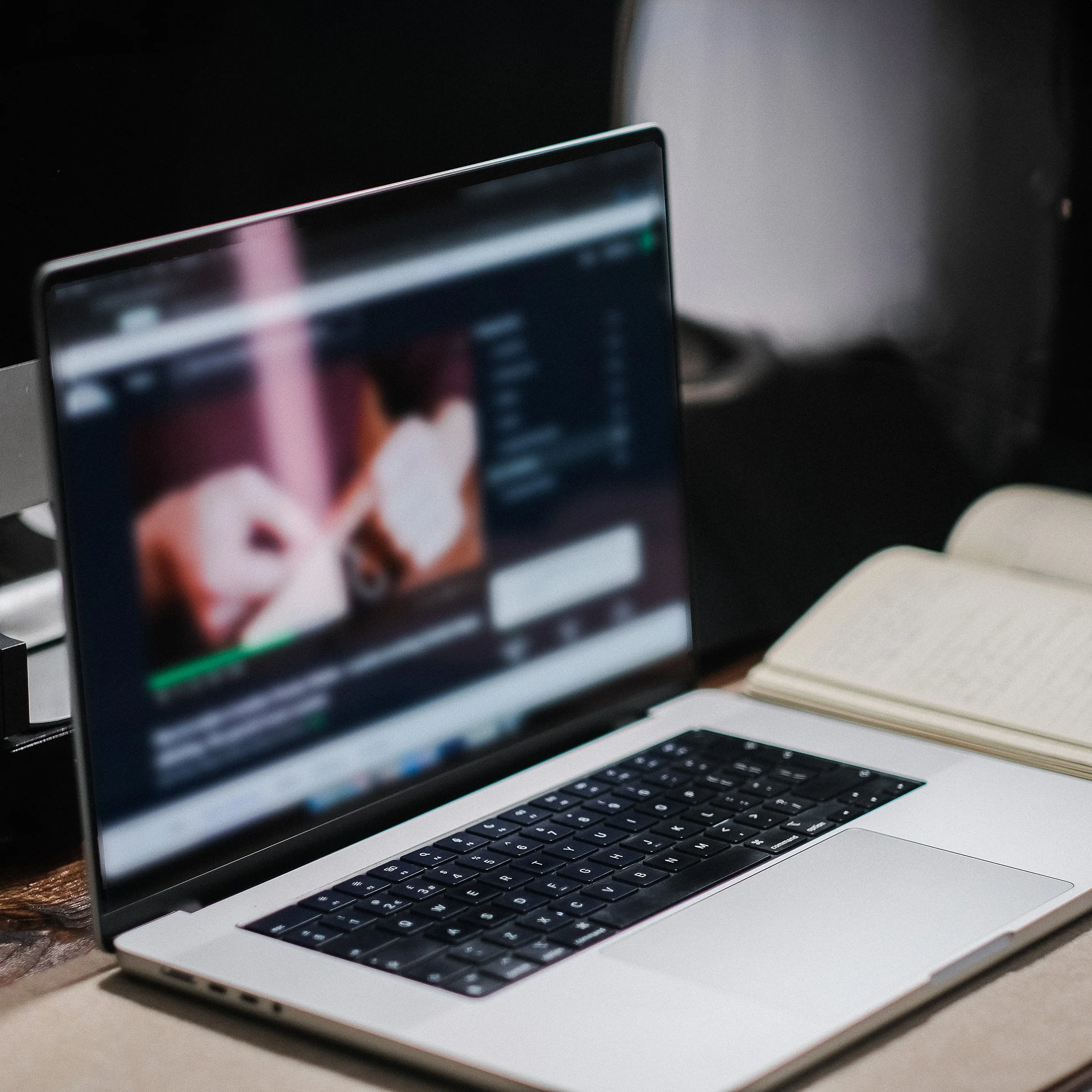 Laptop computer on a desk, with a keyboard visible and a dark background.