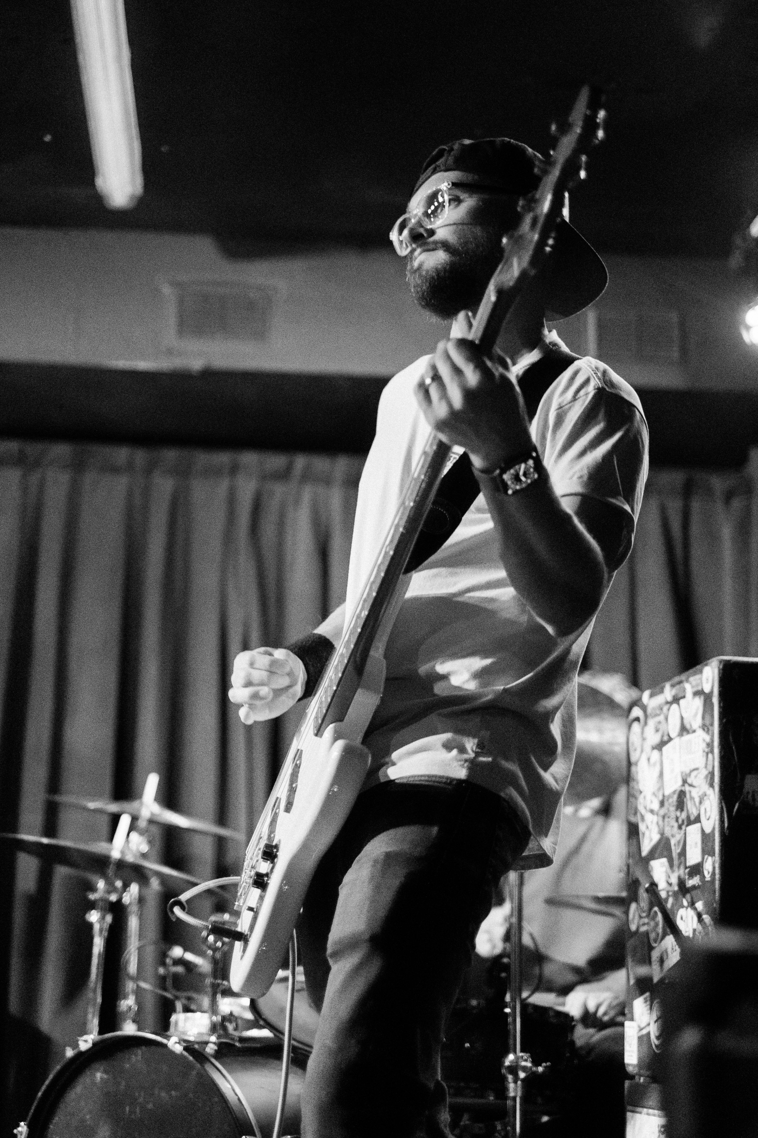 A musician playing an electric guitar on stage in a black and white photo.
