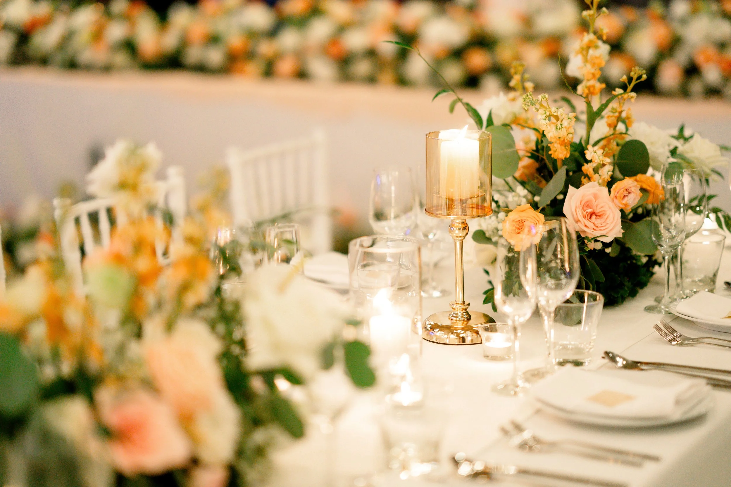 Elegant banquet table decorated with floral arrangements, glowing candles, and glassware.