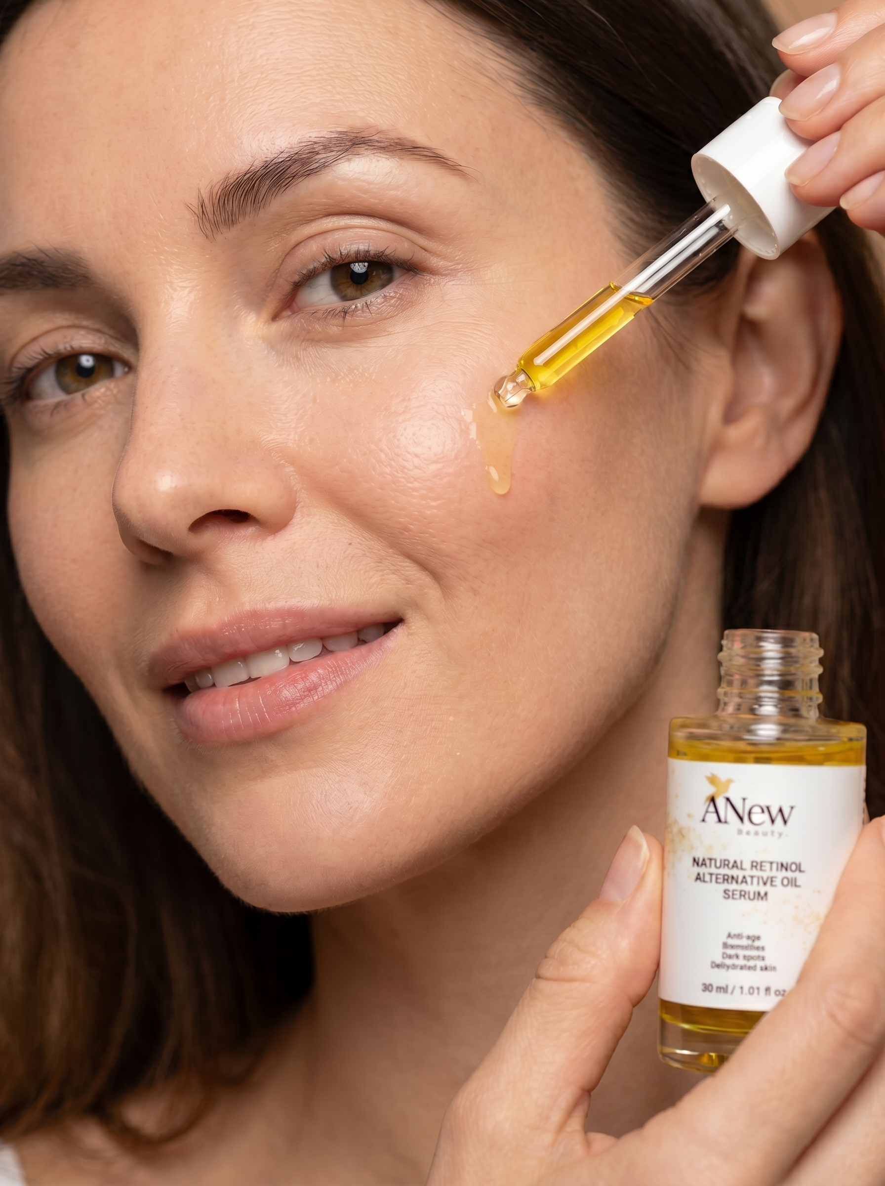 A woman with brown hair applying a golden-colored serum to her cheek using a dropper from a small bottle labeled 'A New Beauty,' which contains natural retinol alternative oil.