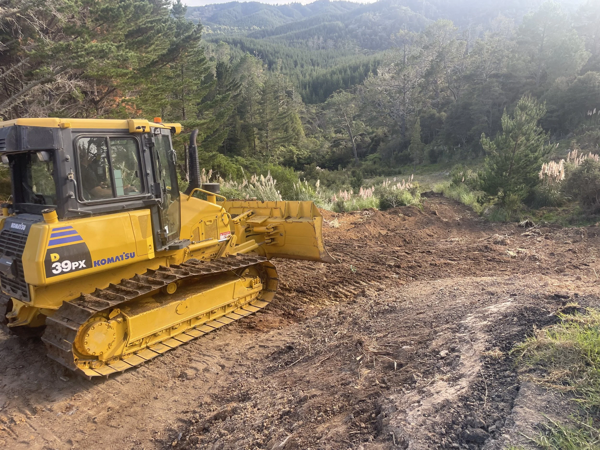A bulldozer moving spoil into valley to create more usable land for property
