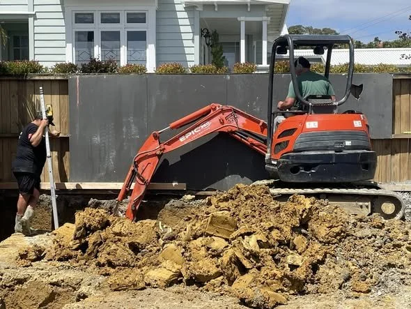 Builder guiding digger operator with footings 