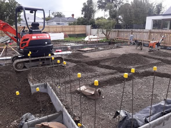 Digger on building worksite for footings and foundations poured. Backfilling with metal