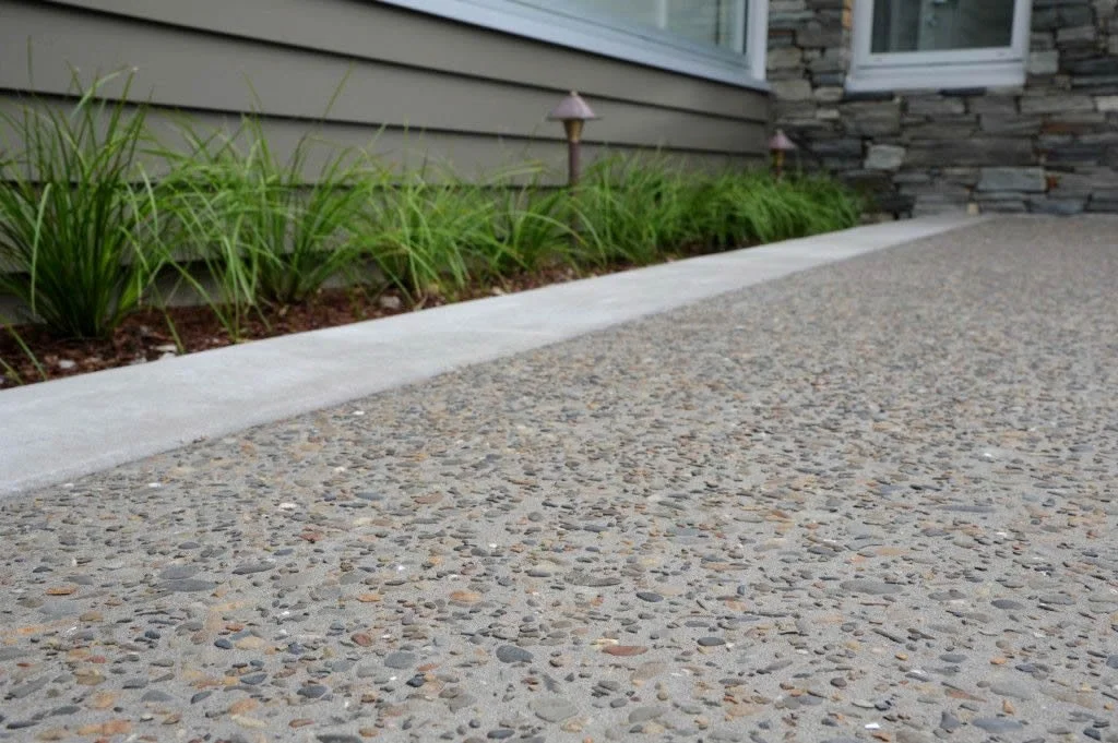 Close-up of a concrete driveway with pebble embedded surface, that has had an acid wash to expose pebbles for this desired look