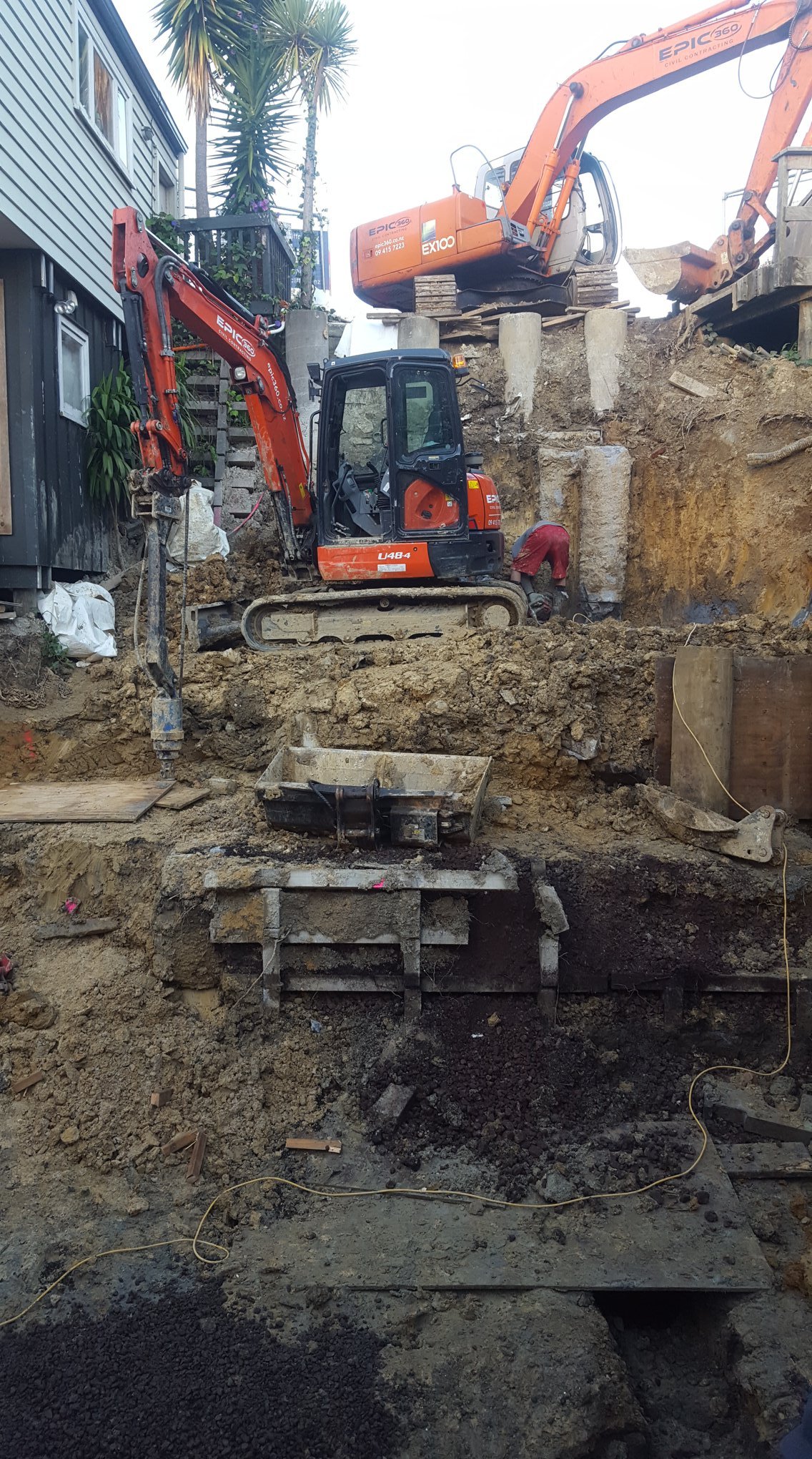Construction site with excavation of ground, showing pilings that have been put in place to support a pool being installed