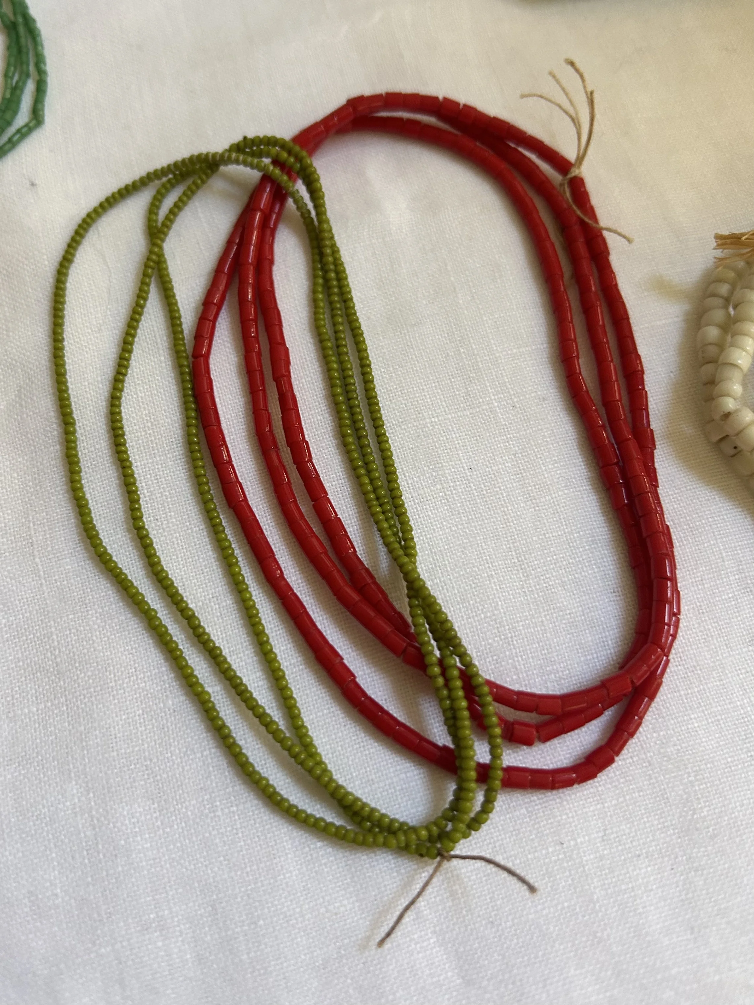 Close-up of multicolored beaded necklaces on a white fabric surface.