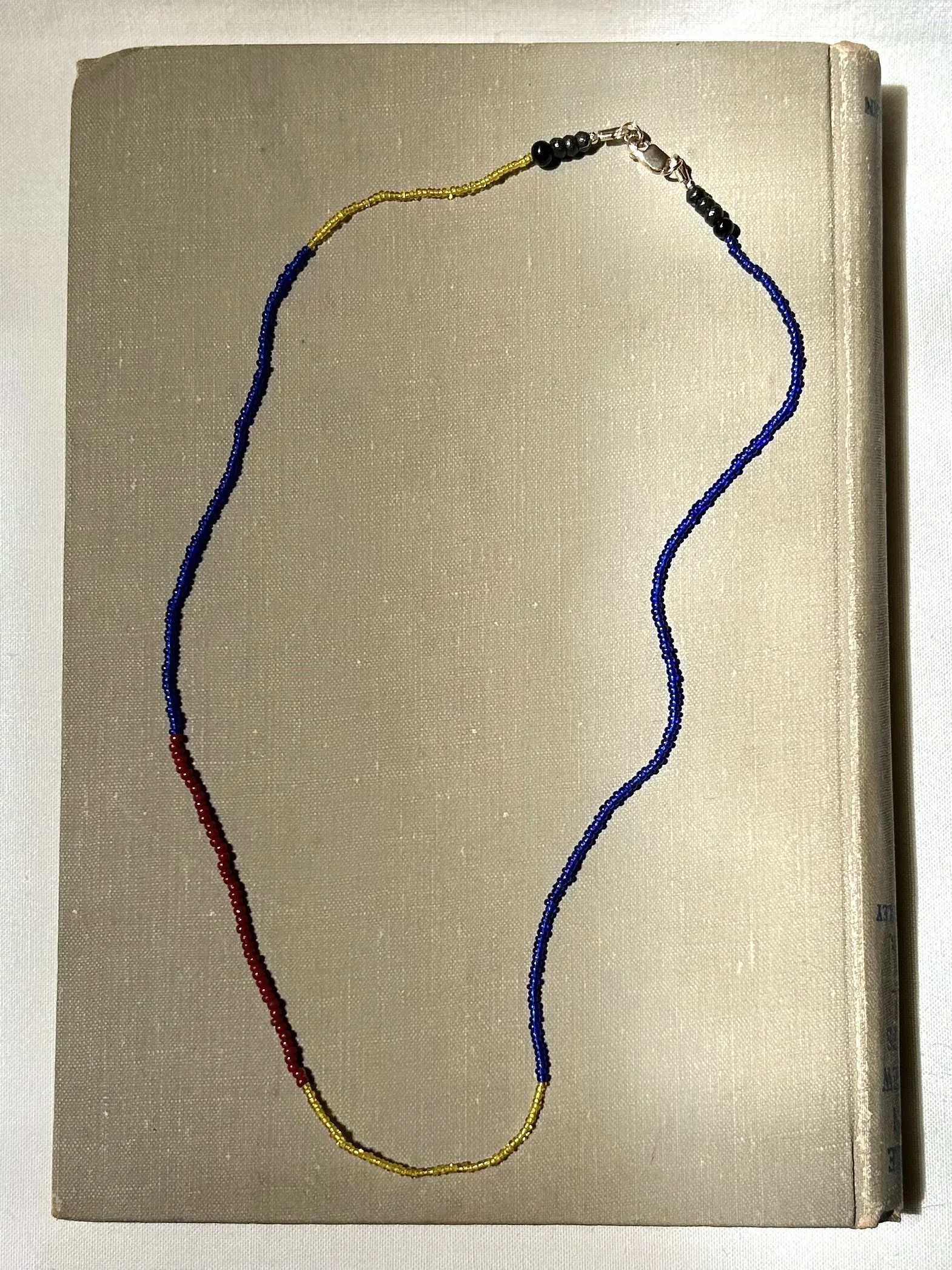 Necklaces with black, red, yellow, and blue beads arranged on a beige book cover.