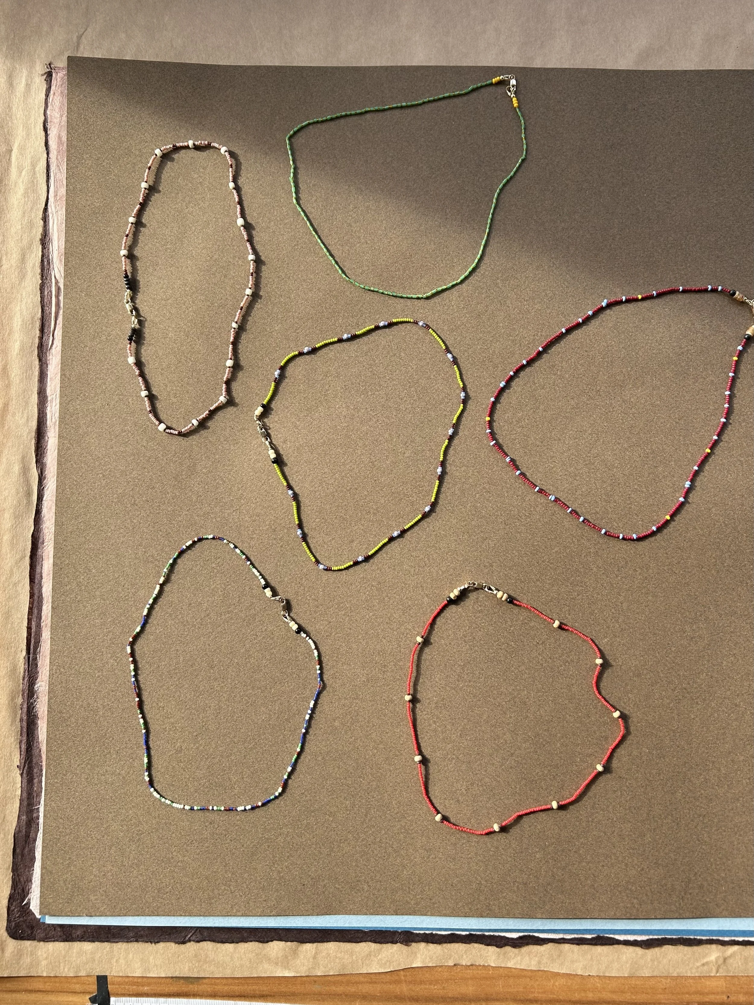 Collection of colorful beaded necklaces arranged on a brown display board.
