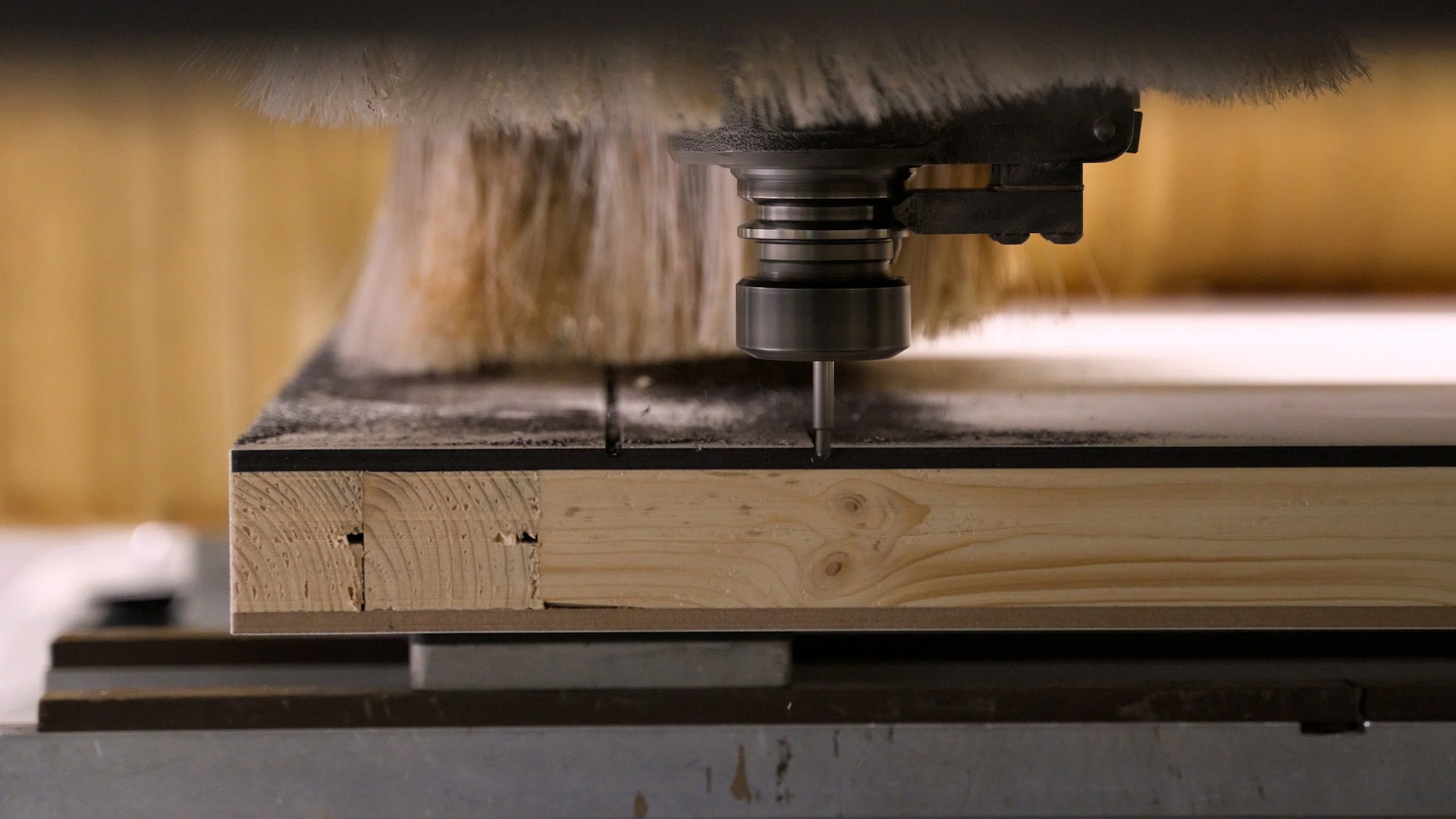Close-up of a machine drilling into a piece of wood on a workbench.