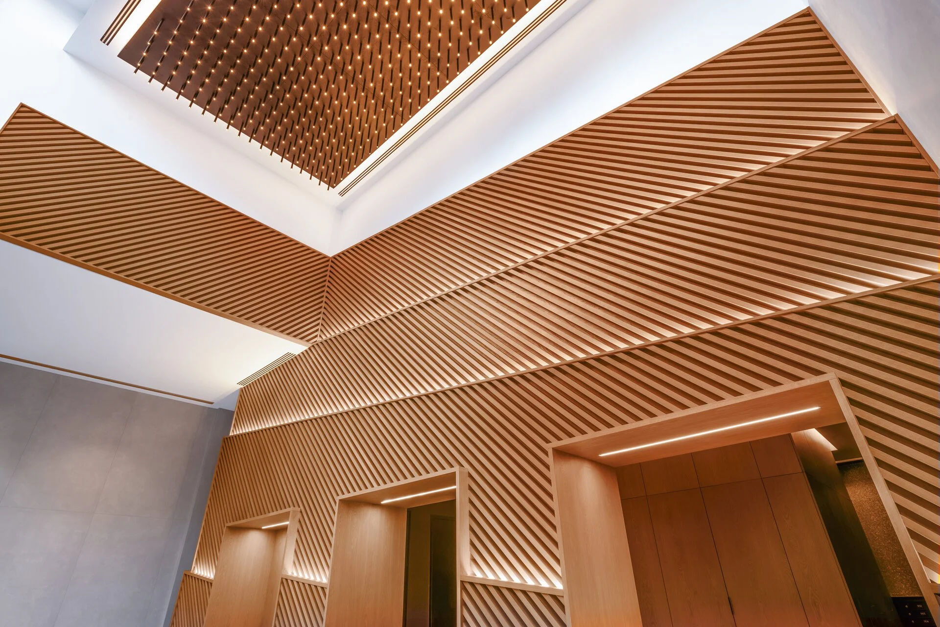 Interior view of ceiling with wooden slats and recessed lighting in a modern building.