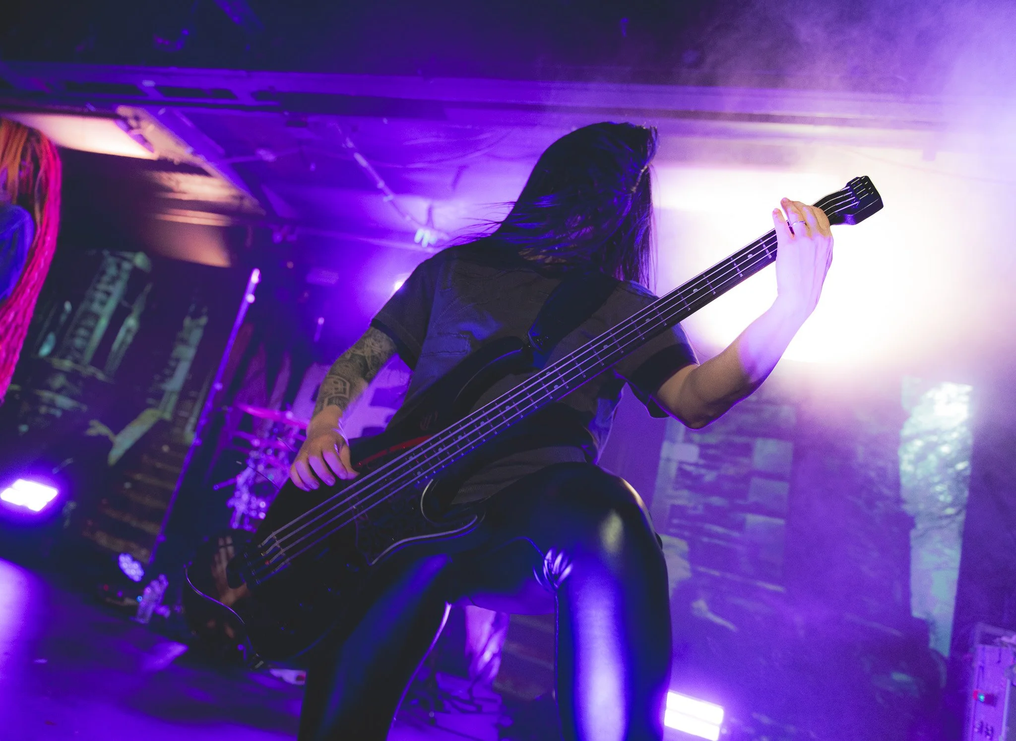 a guitarist performing on stage with purple lighting