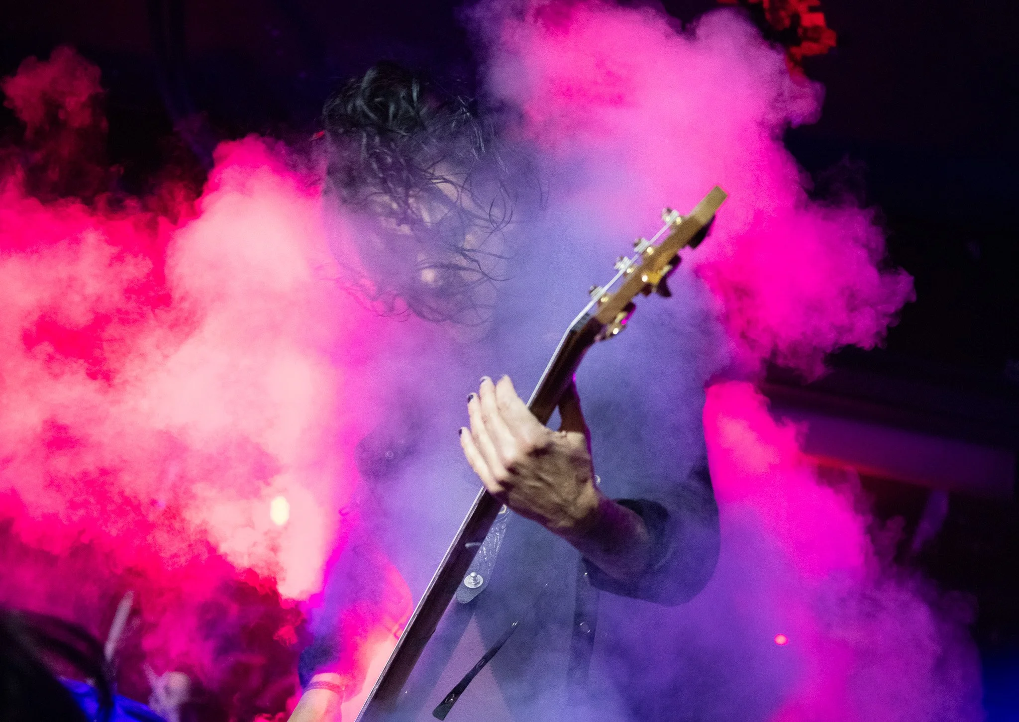 a guitarist performing in haze in a PNW venue