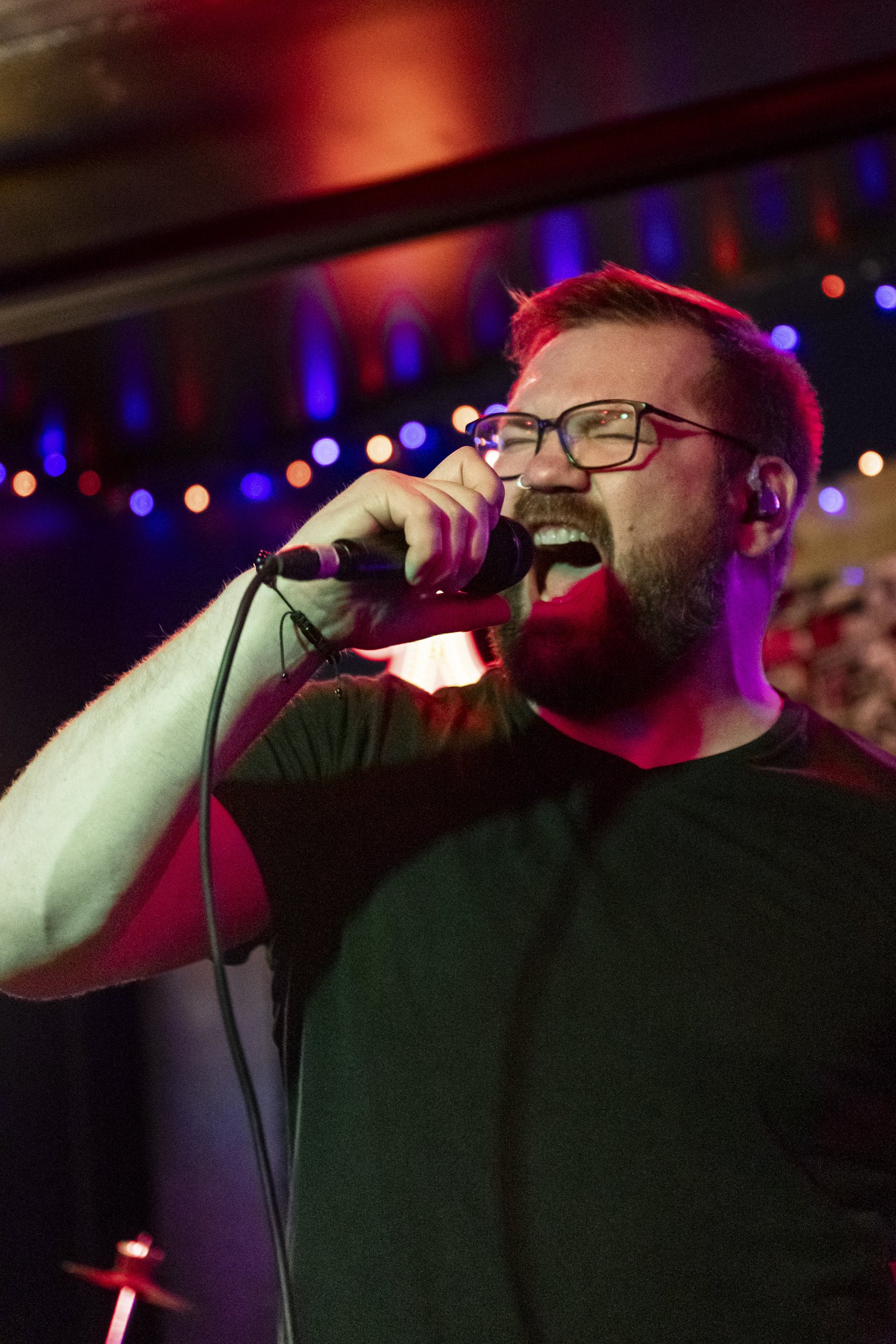 A man singing on stage during a metal concert in the PNW