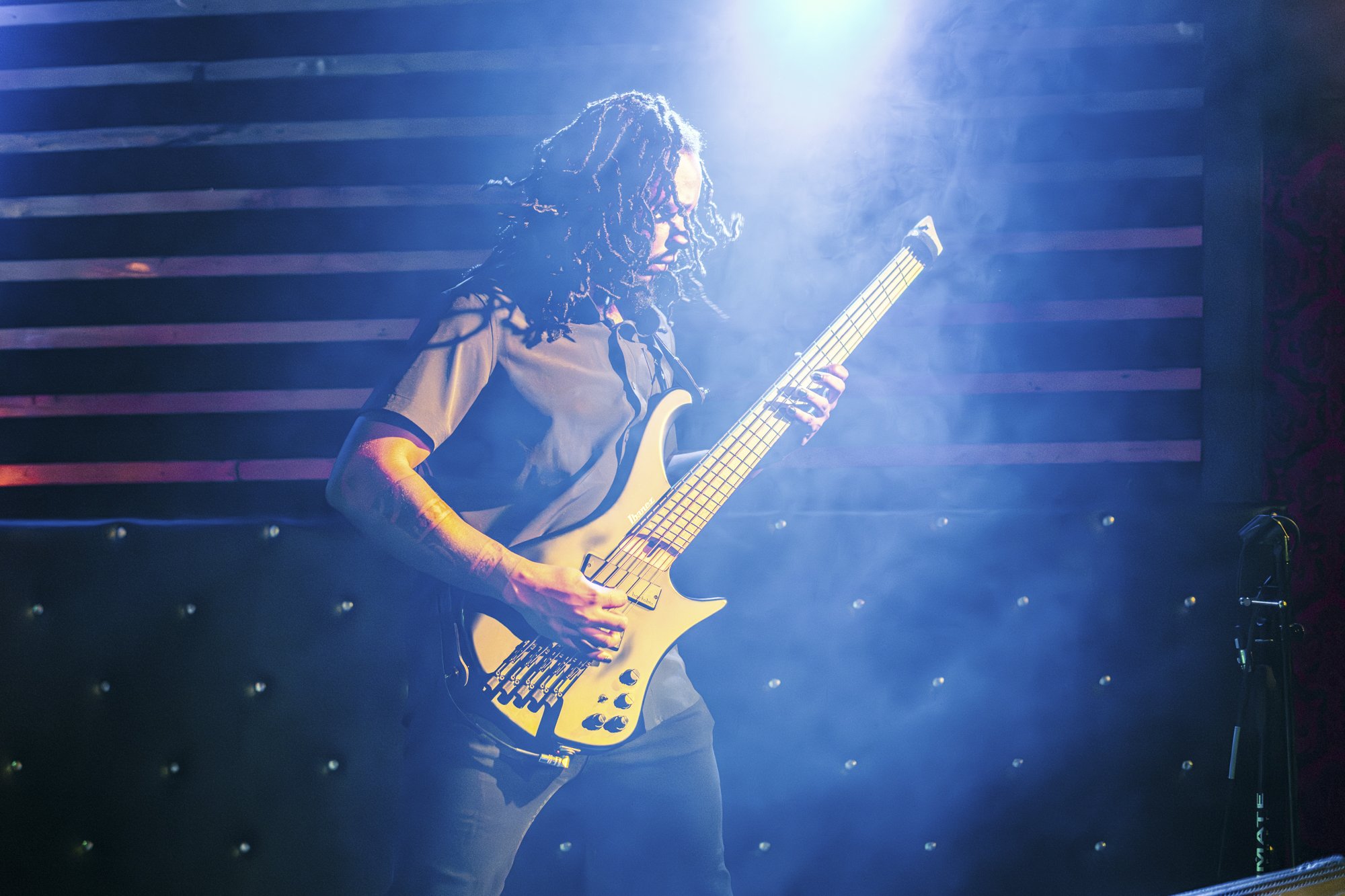 A guitarist under bright stage lights playing in a PNW music venue