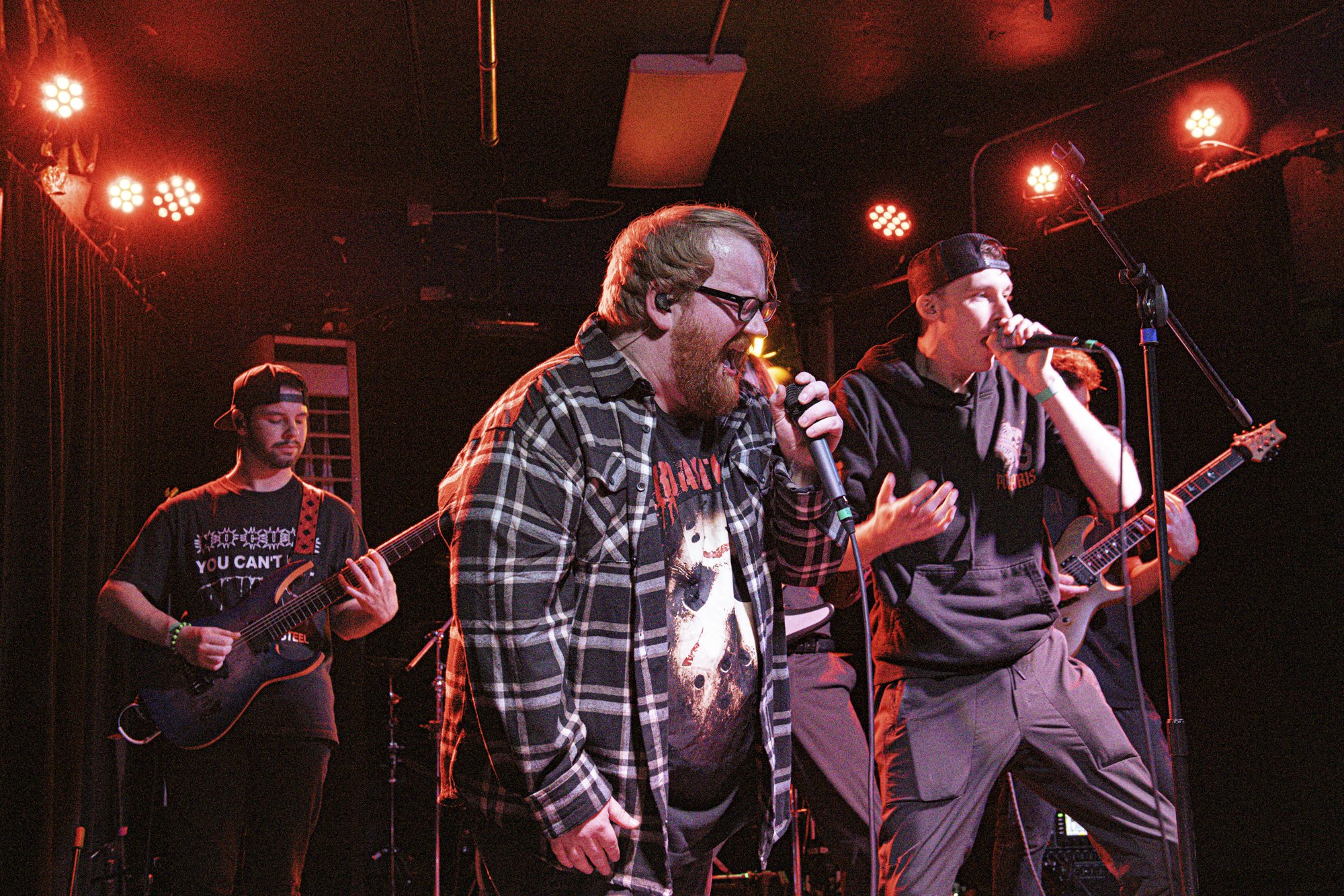 A metal band performing under red stage lights