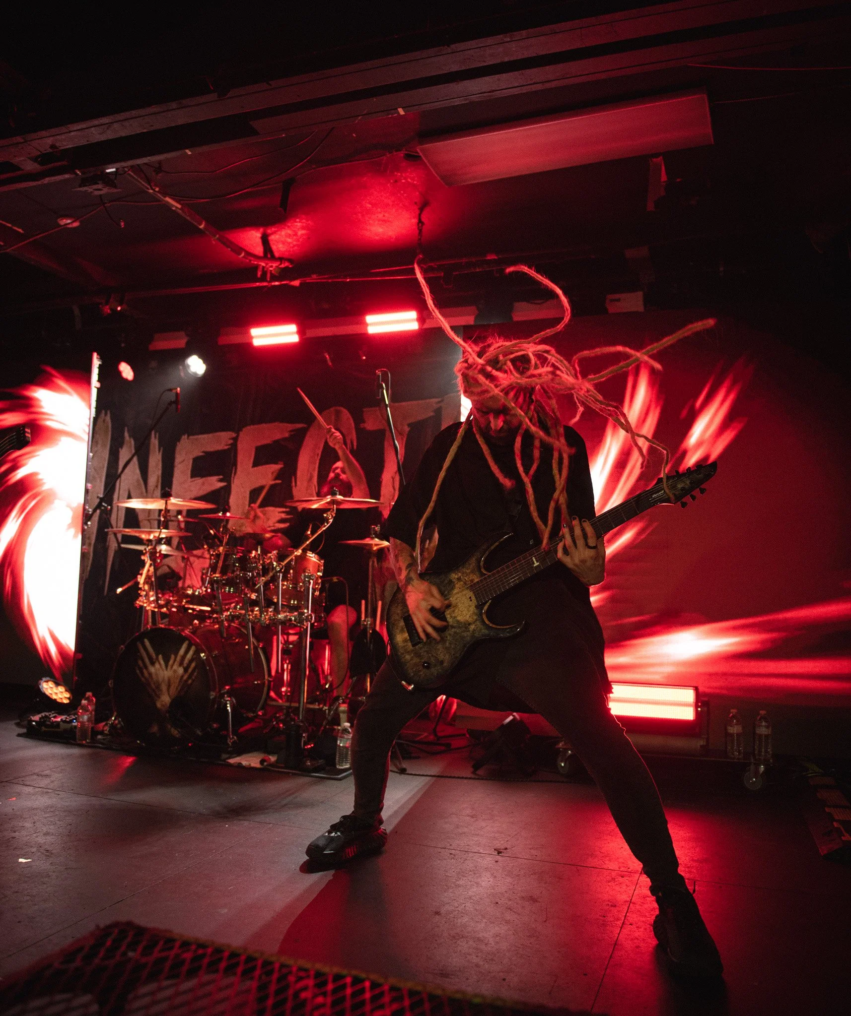 a guitarist performing on stage with red stage lights
