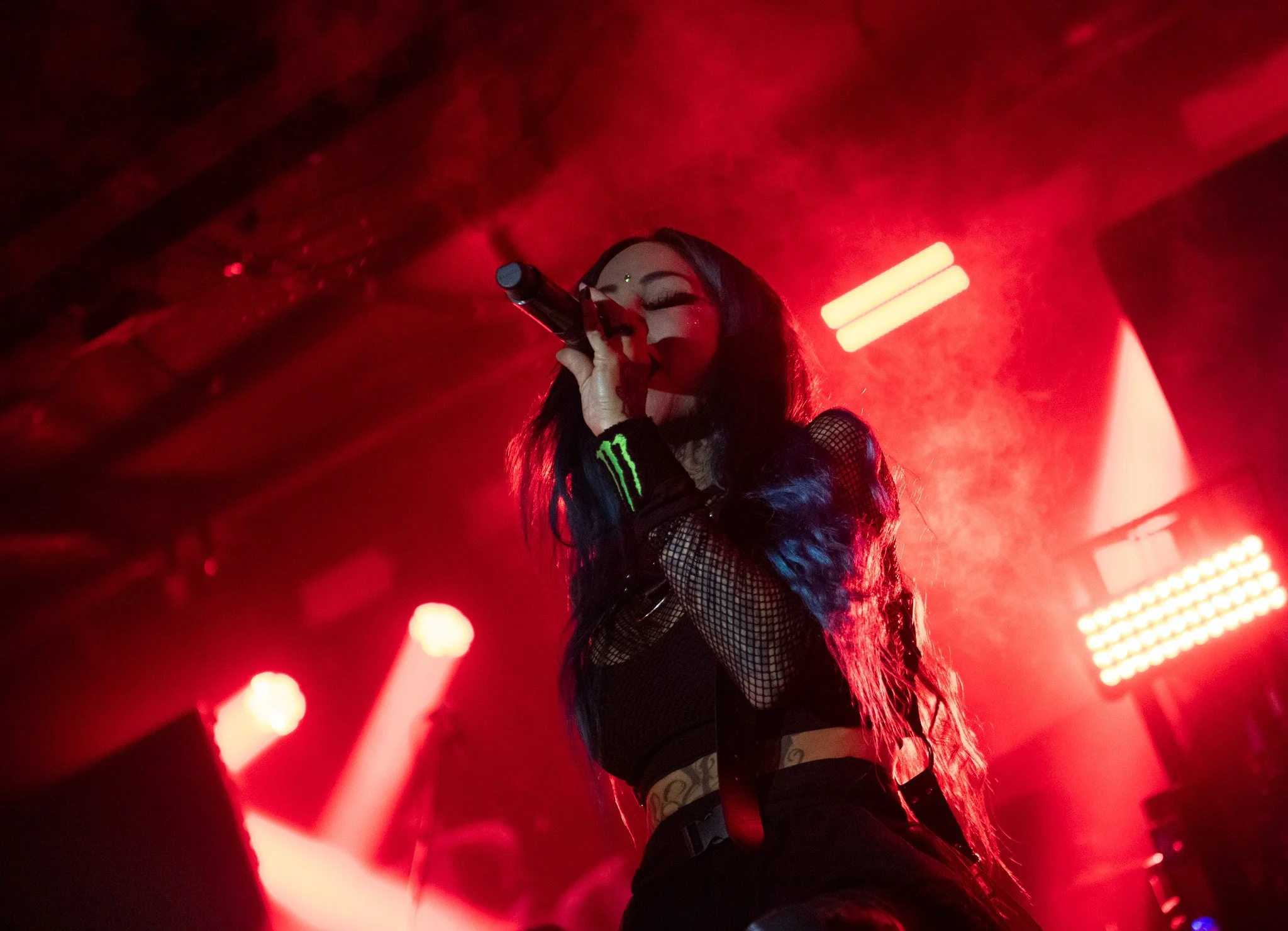 A woman singing surrounded by red lighting