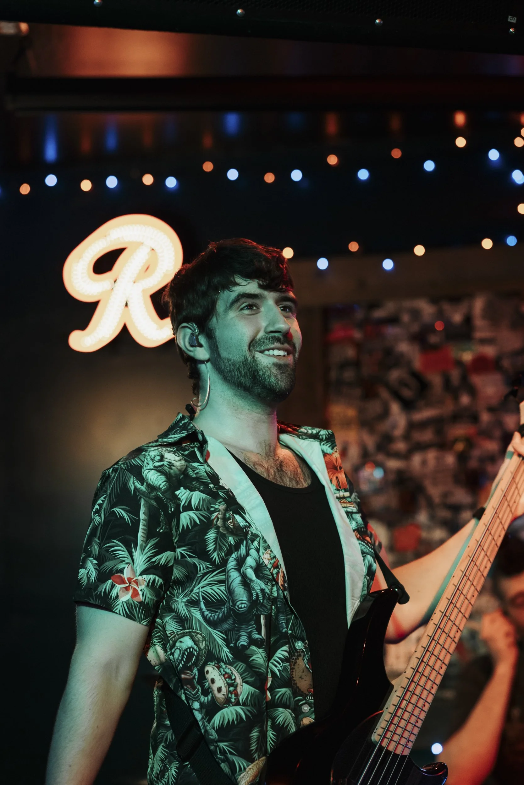 A musician smiling on stage at a PNW venue