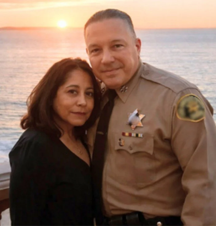 Alex Villanueva with his wife Vivian, close together by the water at sunset.