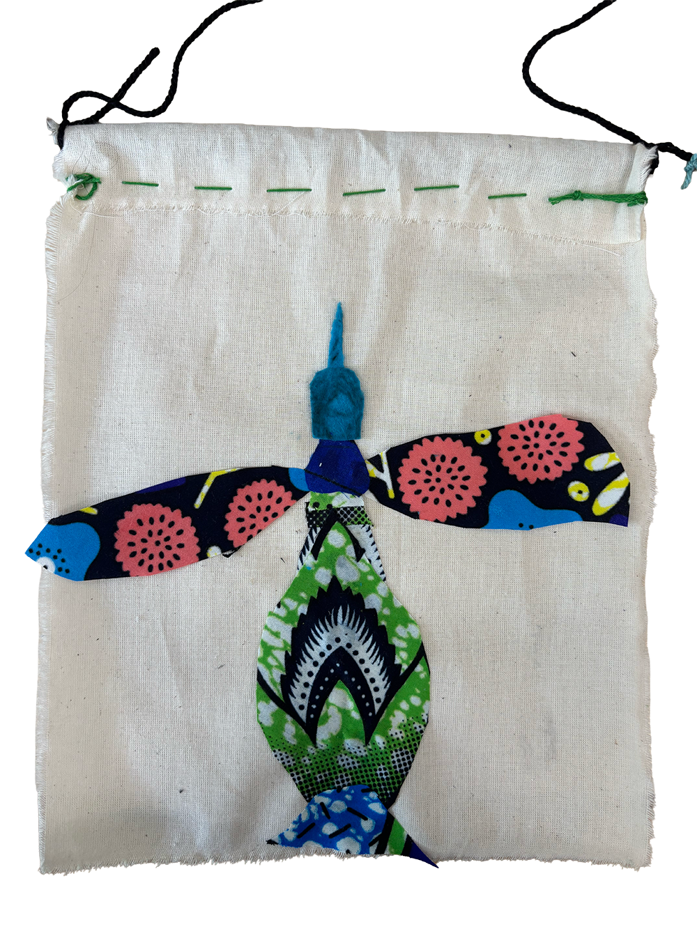 Fabric applique of a colorful dragonfly with black, pink, blue, green, and white patterns on a white cloth background.