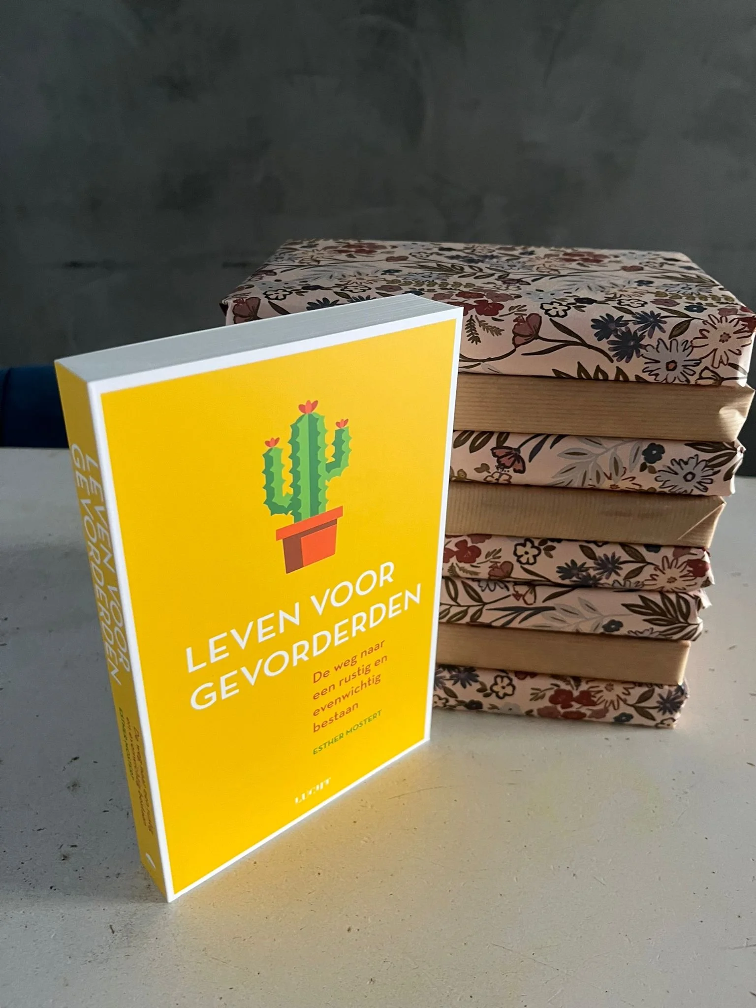 Een stapel boeken met een felgele kop en een boek met een bloemenpatroon en een boek met een bloemenpatroon