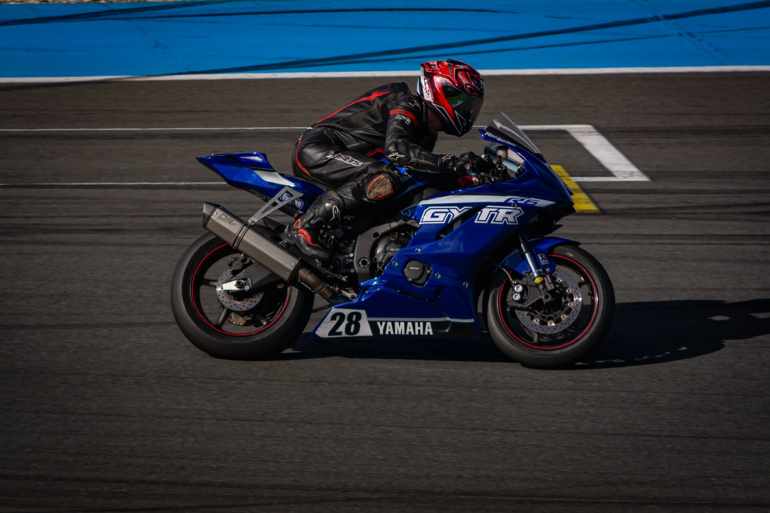 Een coureur rijdt op een blauwe Yamaha sportmotor op een racebaan.