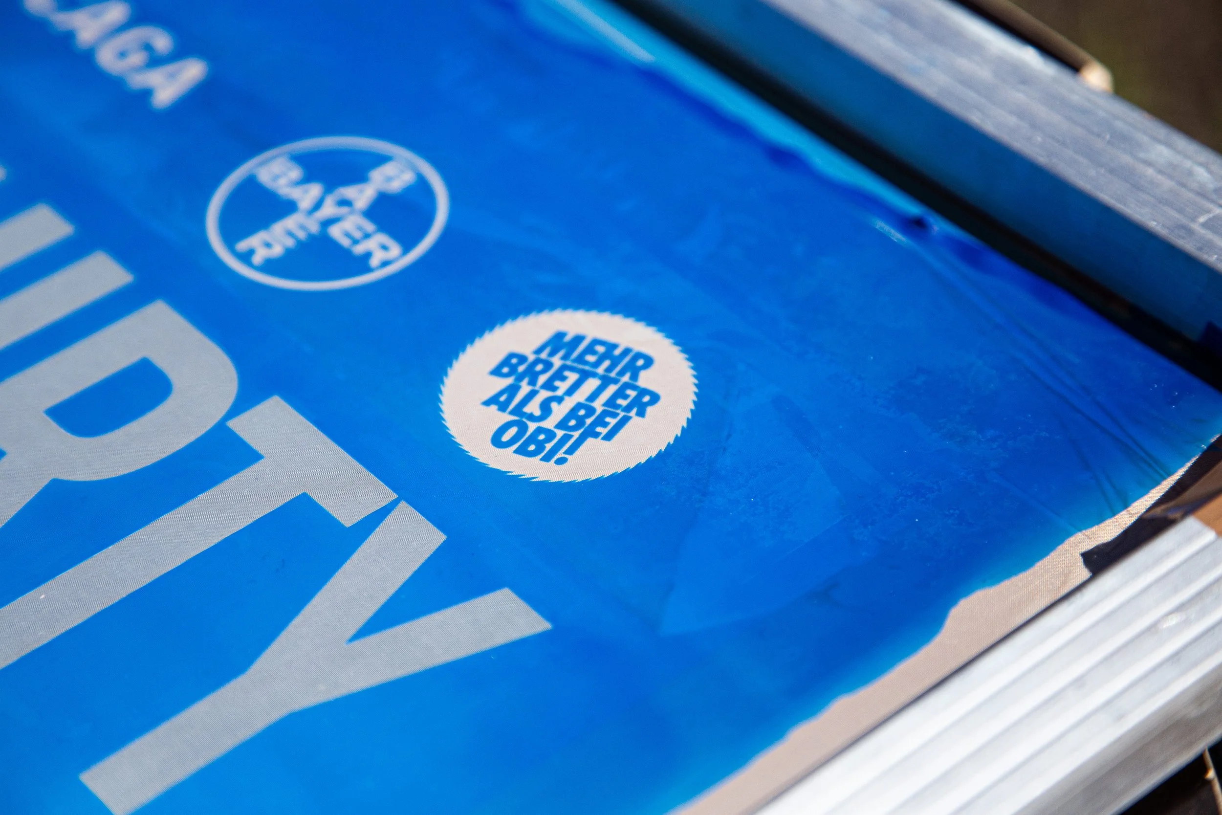 Close-up of a blue silkscreen, showing different motifs, being ready for a screenprint session.