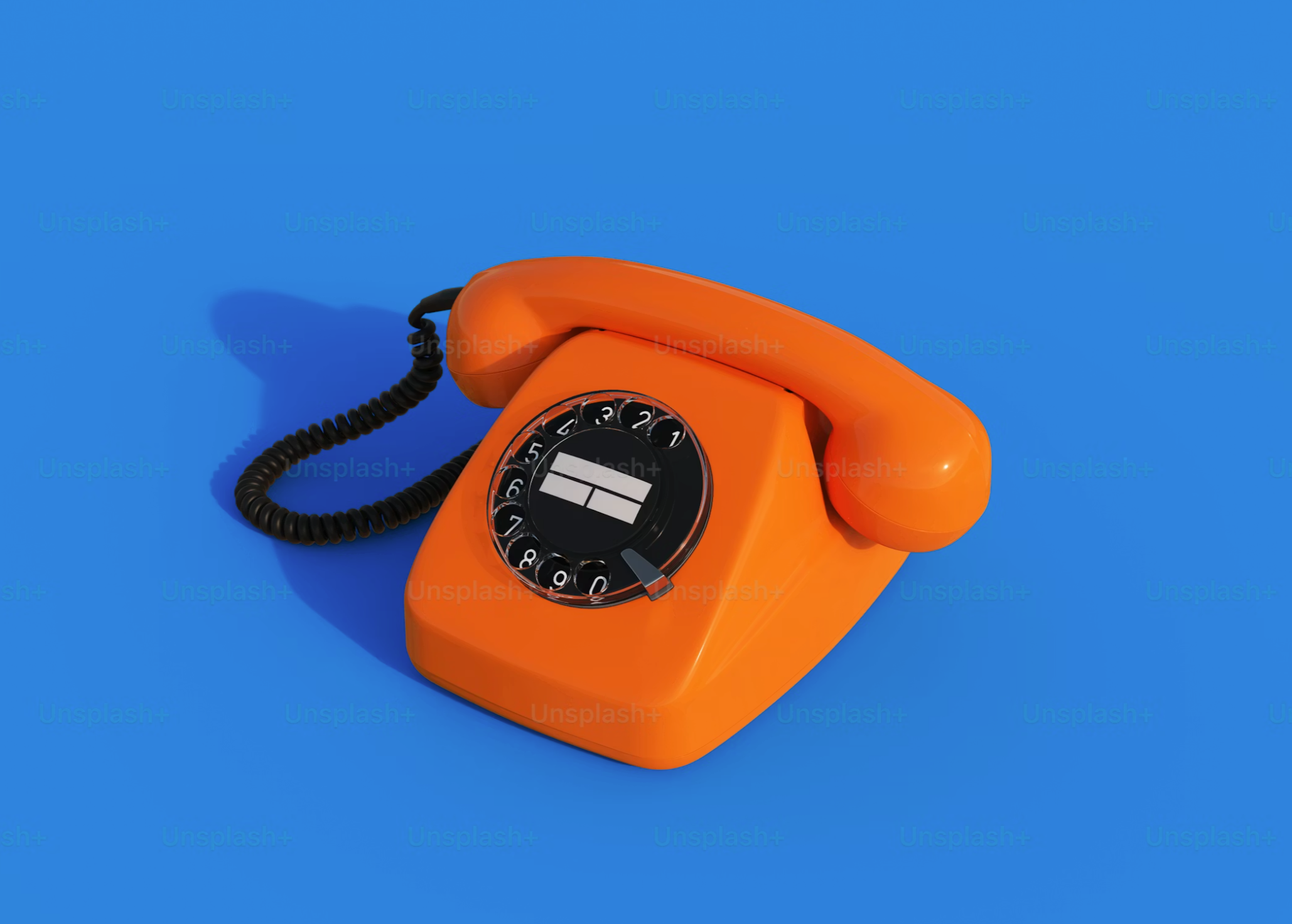 An orange rotary dial telephone placed on a blue surface.