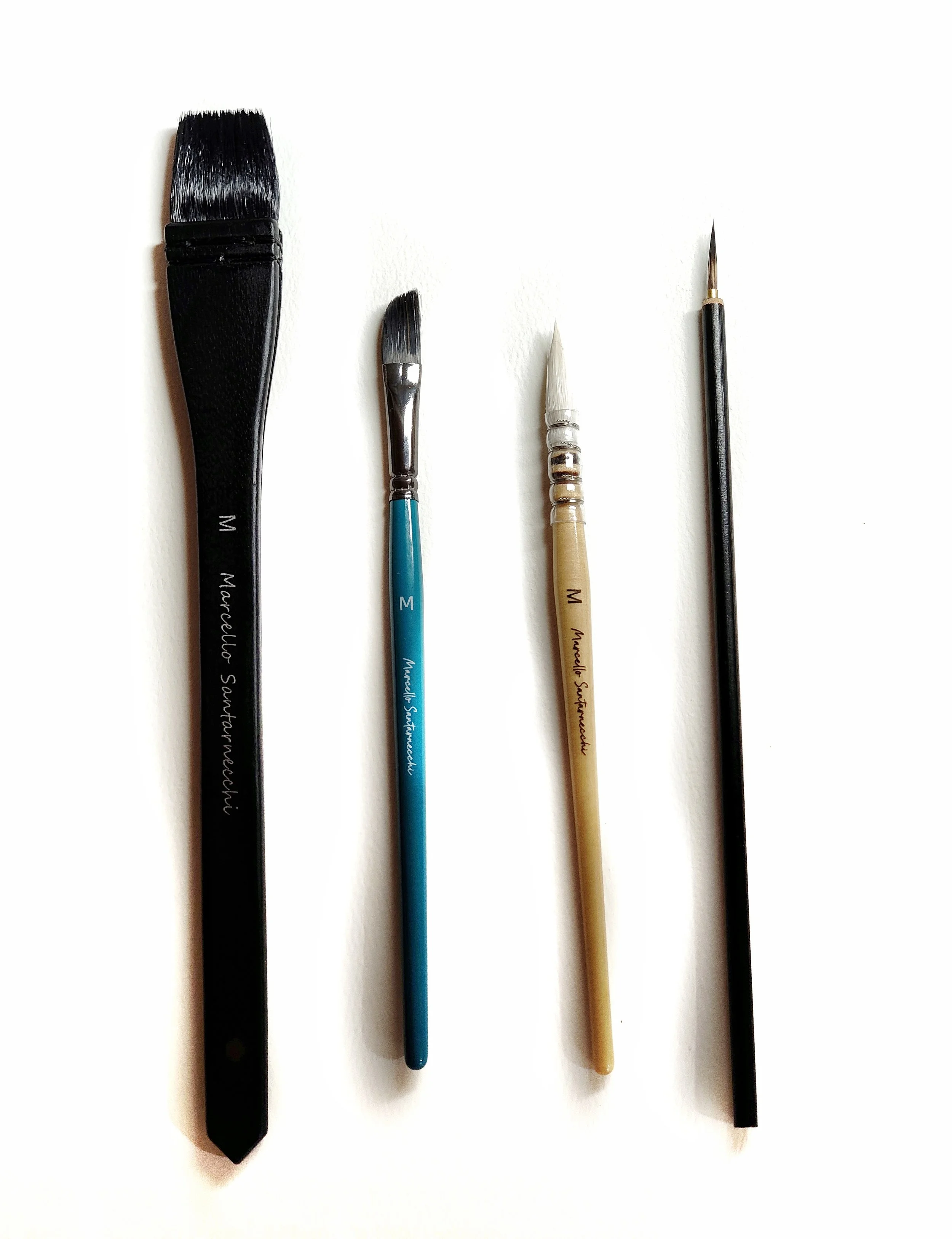 Quatre pinceaux de différentes tailles et formes alignés sur un fond blanc.