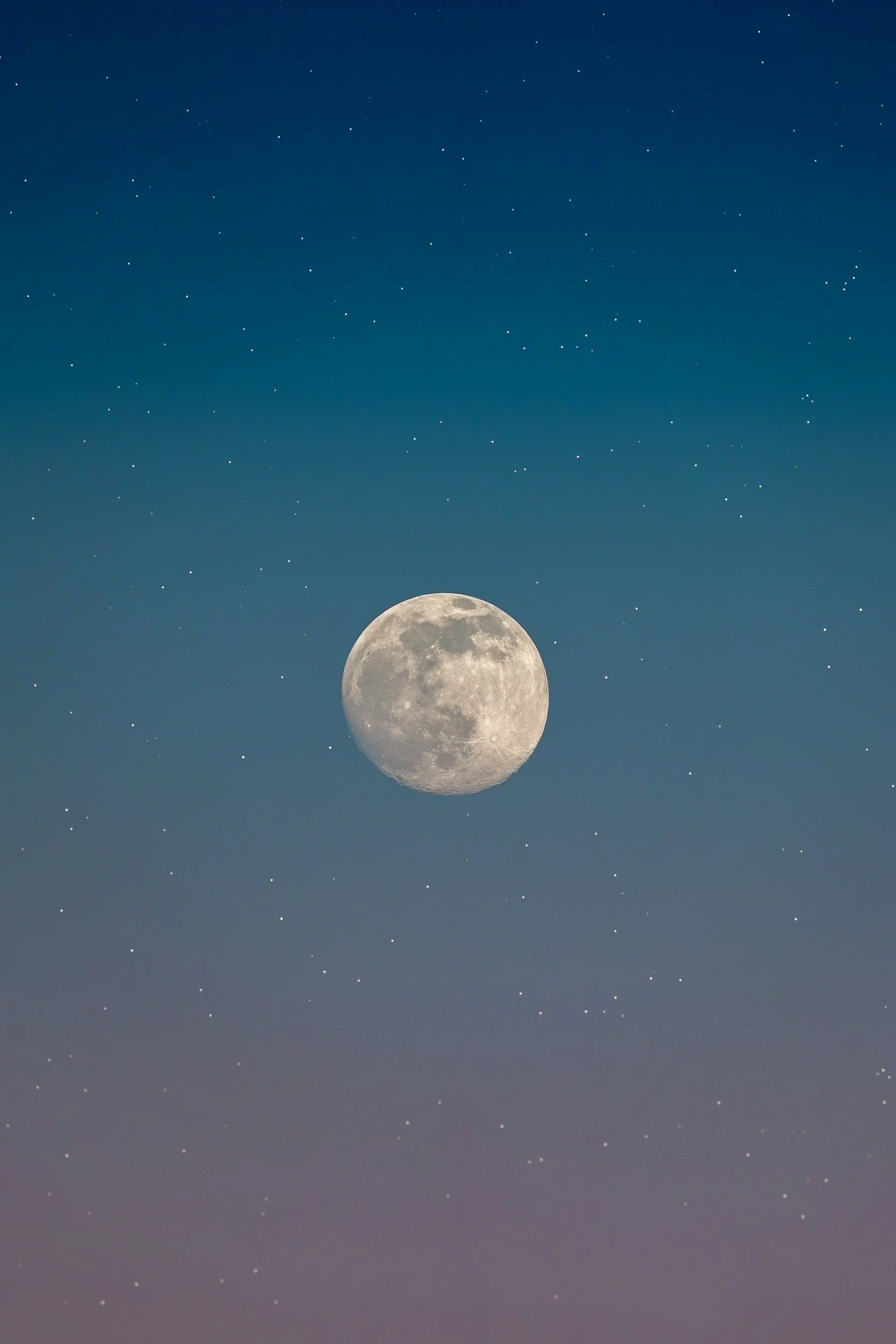 Full moon in a starry night sky with small white stars scattered throughout.