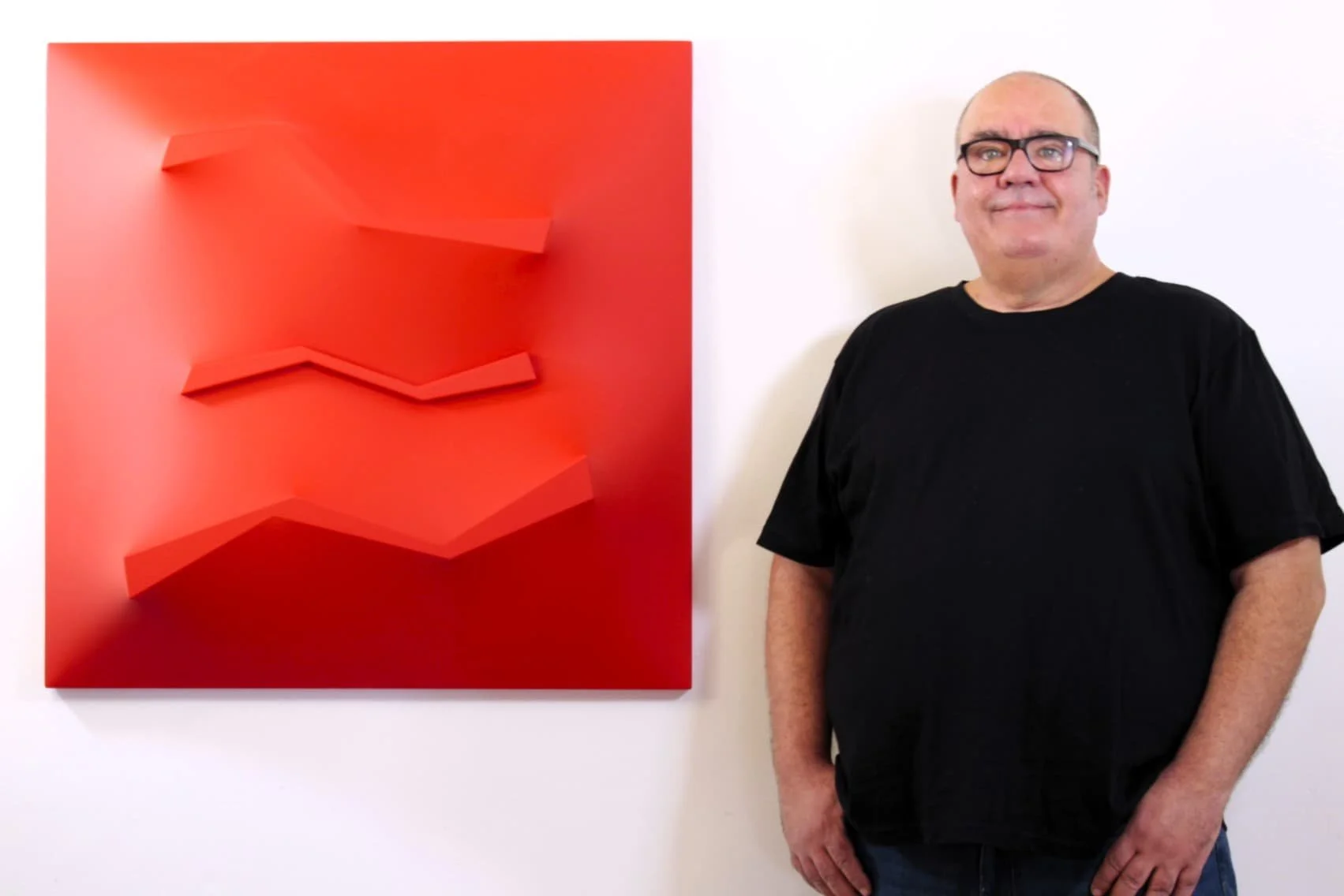 Alessandro Butera, Italian contemporary artist and founder of Alessandro Butera Studio, portrait alongside a large red geometric extroflessed artwork, acrylic on wood, province of Palermo, Italy