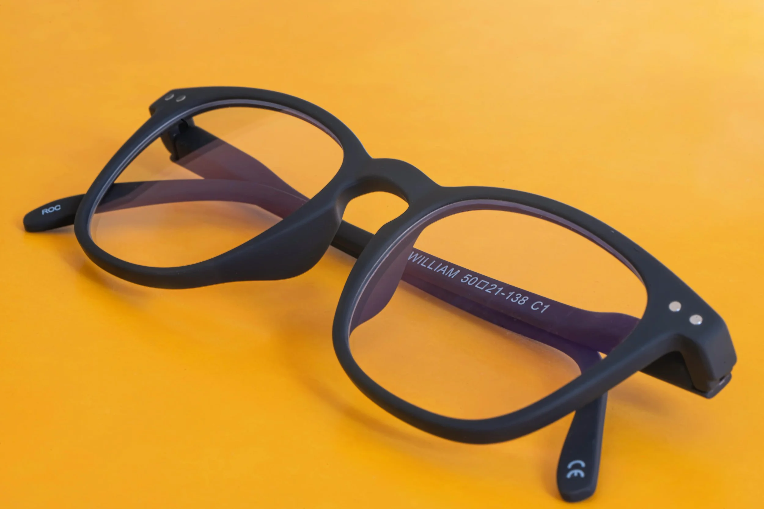A pair of black sports glasses with tinted lenses placed on an orange background.