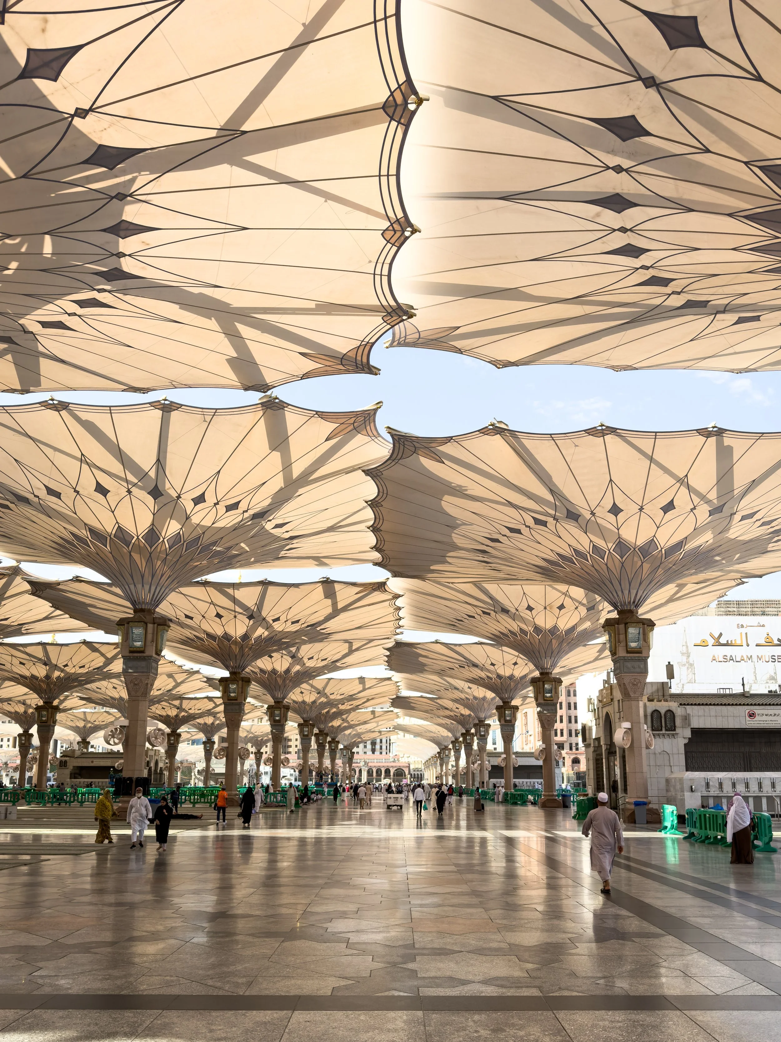 Masjid Nabawi, Medina, Saudi Arabia — The iconic retractable umbrellas of the Prophet's Mosque courtyard, open against the afternoon heat. Seen from below, they become a canopy of geometry — engineering in service of mercy.
