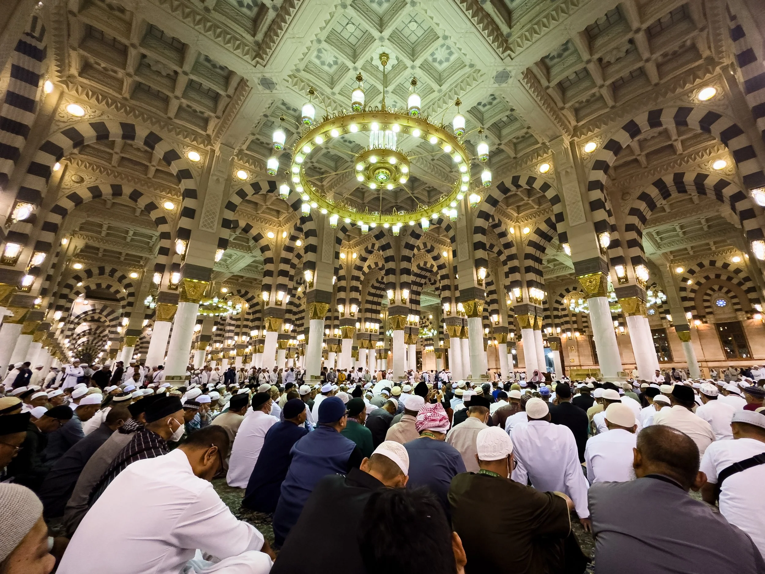 Masjid Nabawi, Medina, Saudi Arabia — Thousands bow in prayer beneath the ornate arches and chandeliers of the Prophet's Mosque. Every face turned in the same direction. Every intention, the same.
