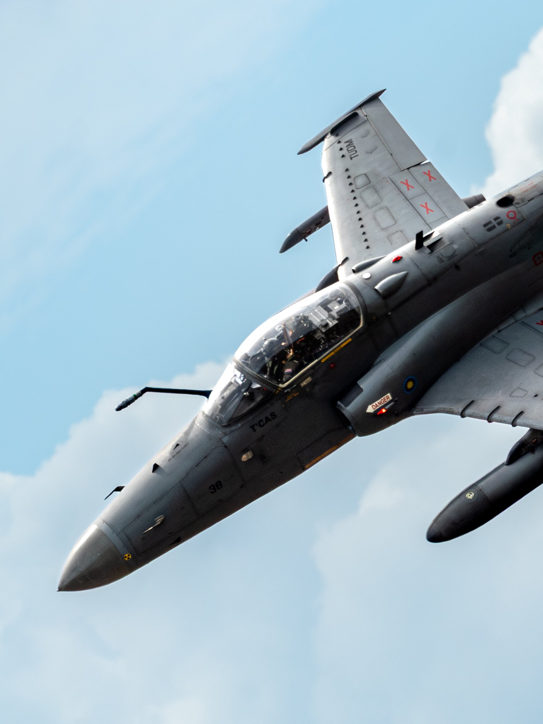 RMAF Hawk 208, TUDM Kuantan, Pahang — The matte black Hawk 208 banks hard overhead, close enough to read the "DANGER" placard. A reminder that this is no ordinary air display.