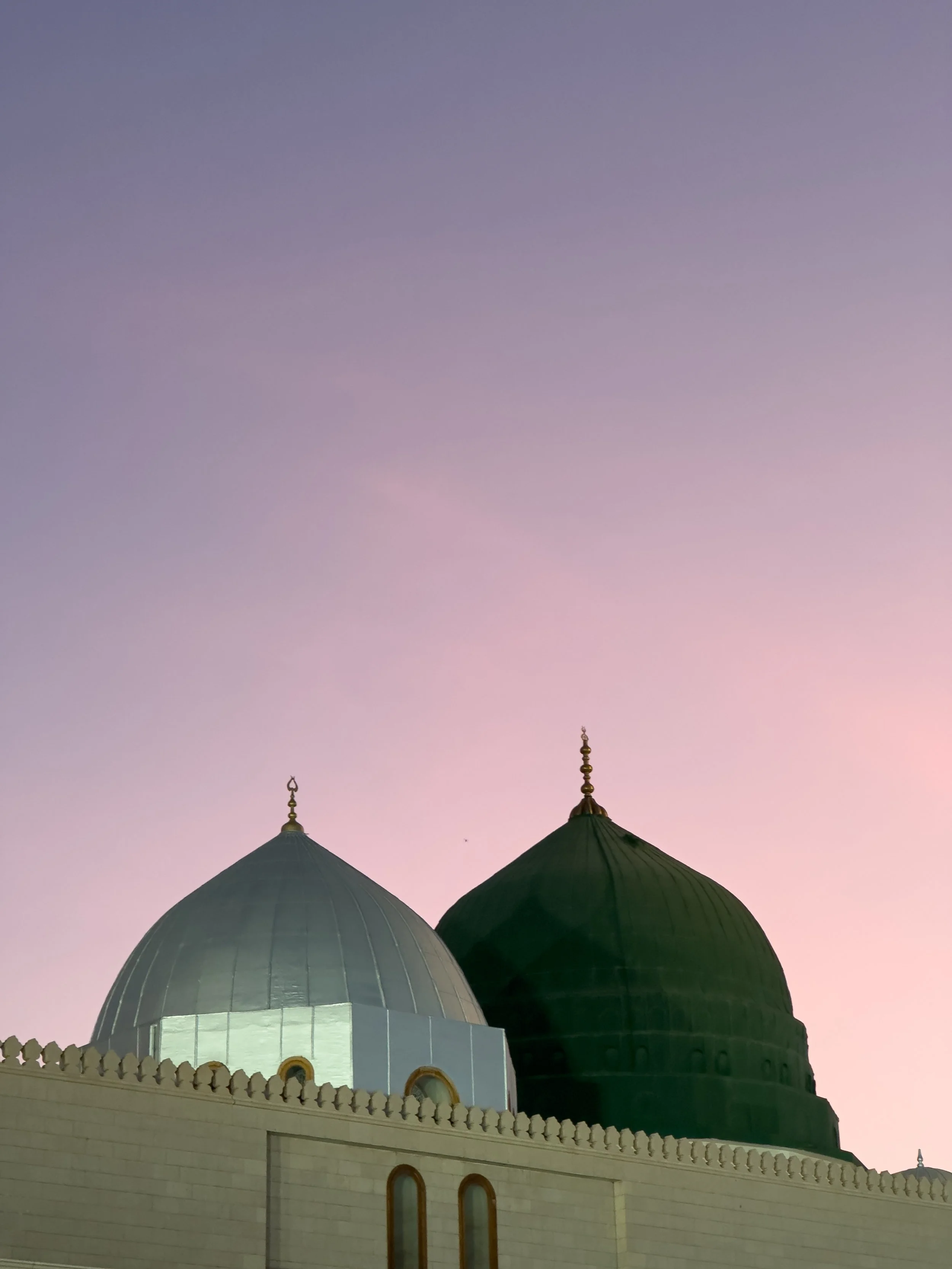 Masjid Nabawi, Medina, Saudi Arabia — The green dome of the Prophet's Mosque at dusk, the sky fading from lavender to rose behind it. One of the most recognisable silhouettes in the Islamic world, reduced to its simplest form.