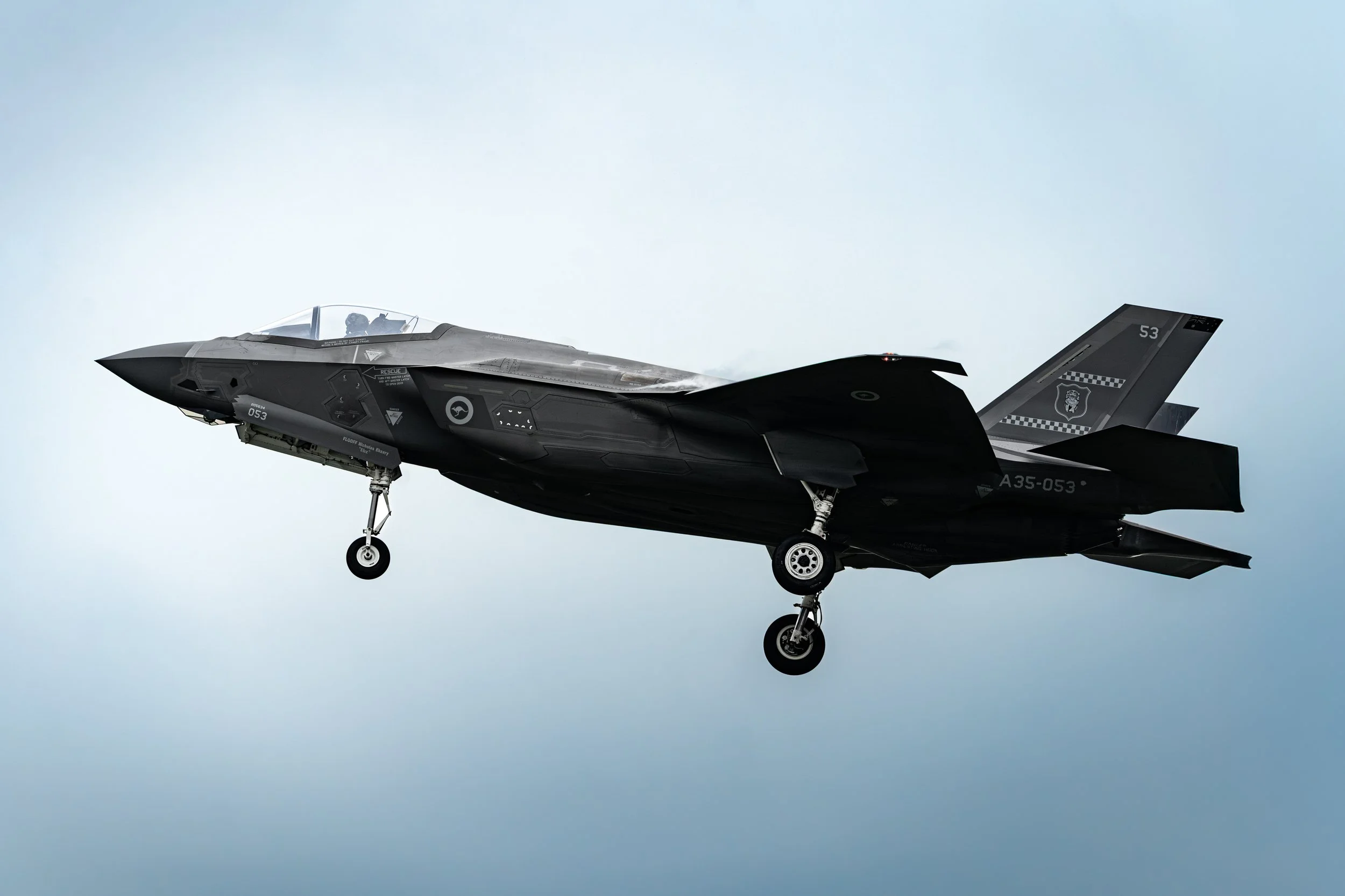 RAAF F-35A Lightning II (A35-053), TUDM Kuantan, Pahang — The RAAF's F-35A slides onto final approach during Exercise Bersama Lima 2025, its matte black stealth skin cutting a clean silhouette against a pale sky.