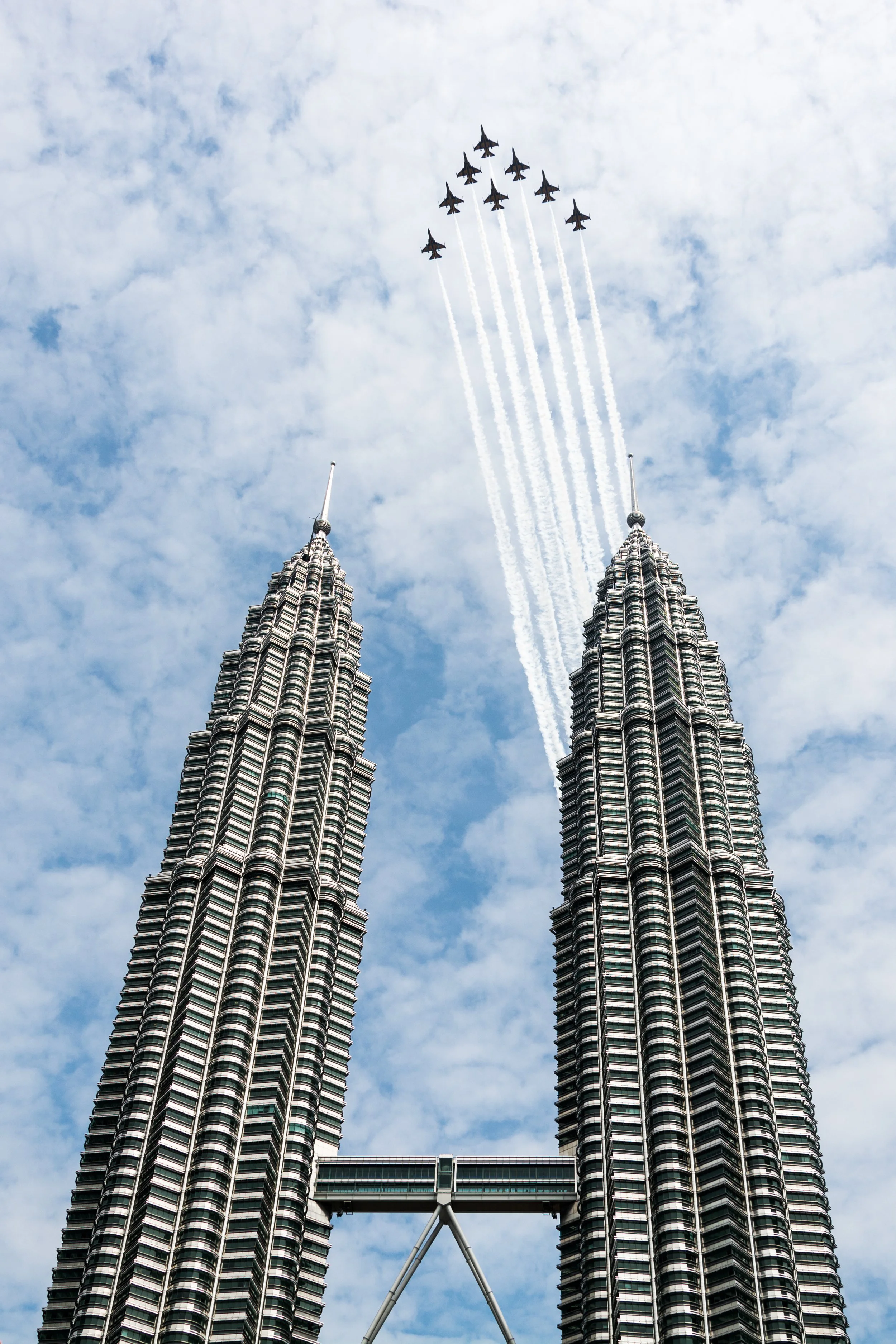 ROKAF Black Eagles over Petronas Twin Towers, Kuala Lumpur — The Black Eagles split the sky directly above the Twin Towers, smoke trails framed perfectly between Malaysia's most iconic skyline. An unrepeatable frame.