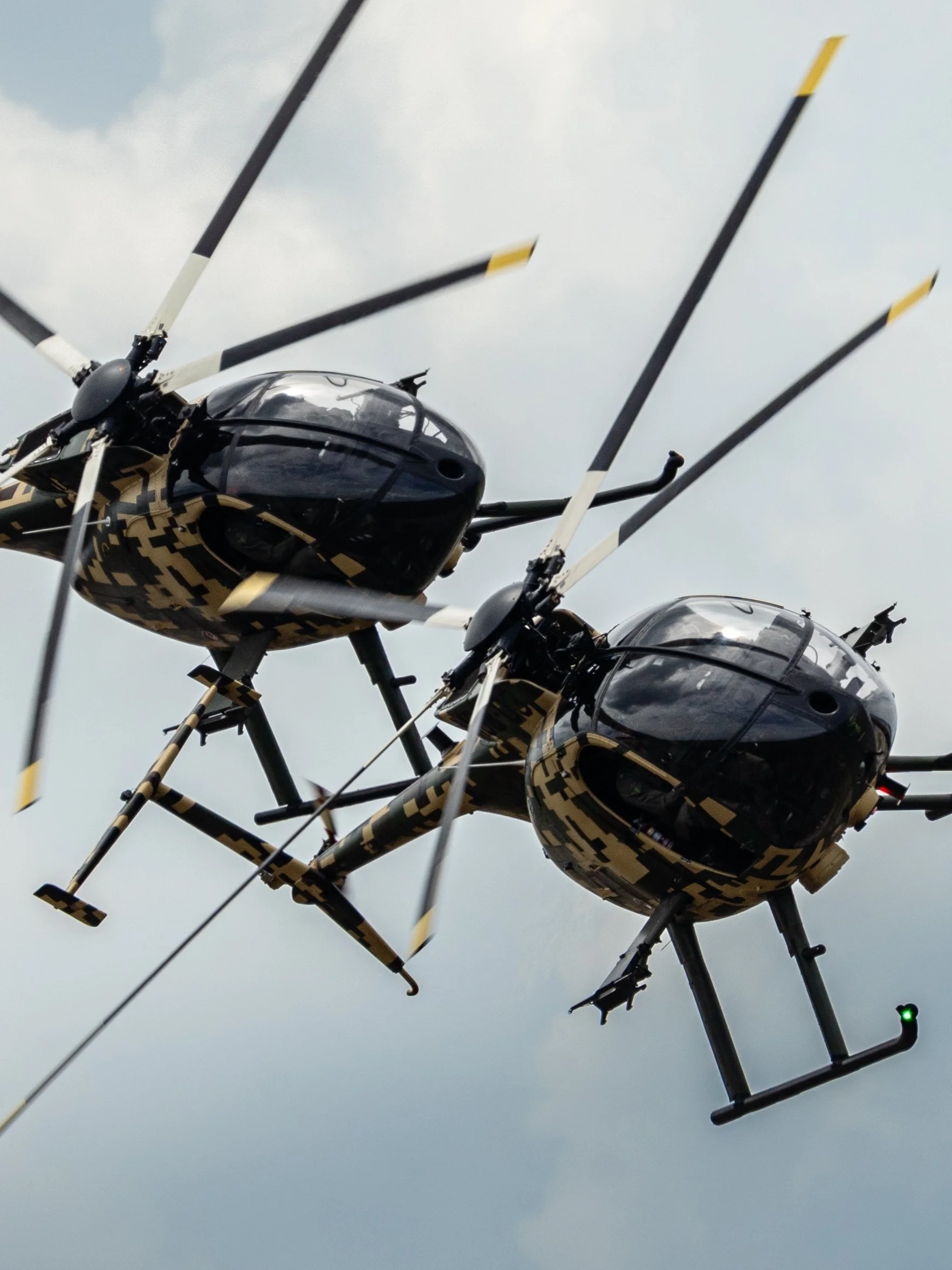 Malaysian Army MD 530G, TUDM Kuantan, Pahang — Two light attack helicopters hold an impossibly tight formation, rotor discs overlapping, blades a breath apart. A display of precision that leaves no room for error.