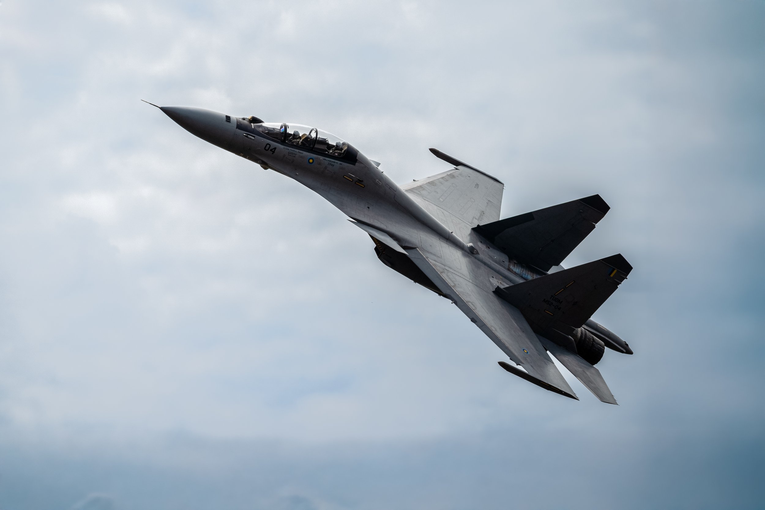 RMAF Su-30MKM, TUDM Kuantan, Pahang — Serial 04 pulls hard through a dramatic cloudscape, vapour condensing across the fuselage. A machine built for dominance, demonstrating exactly what it was built for.