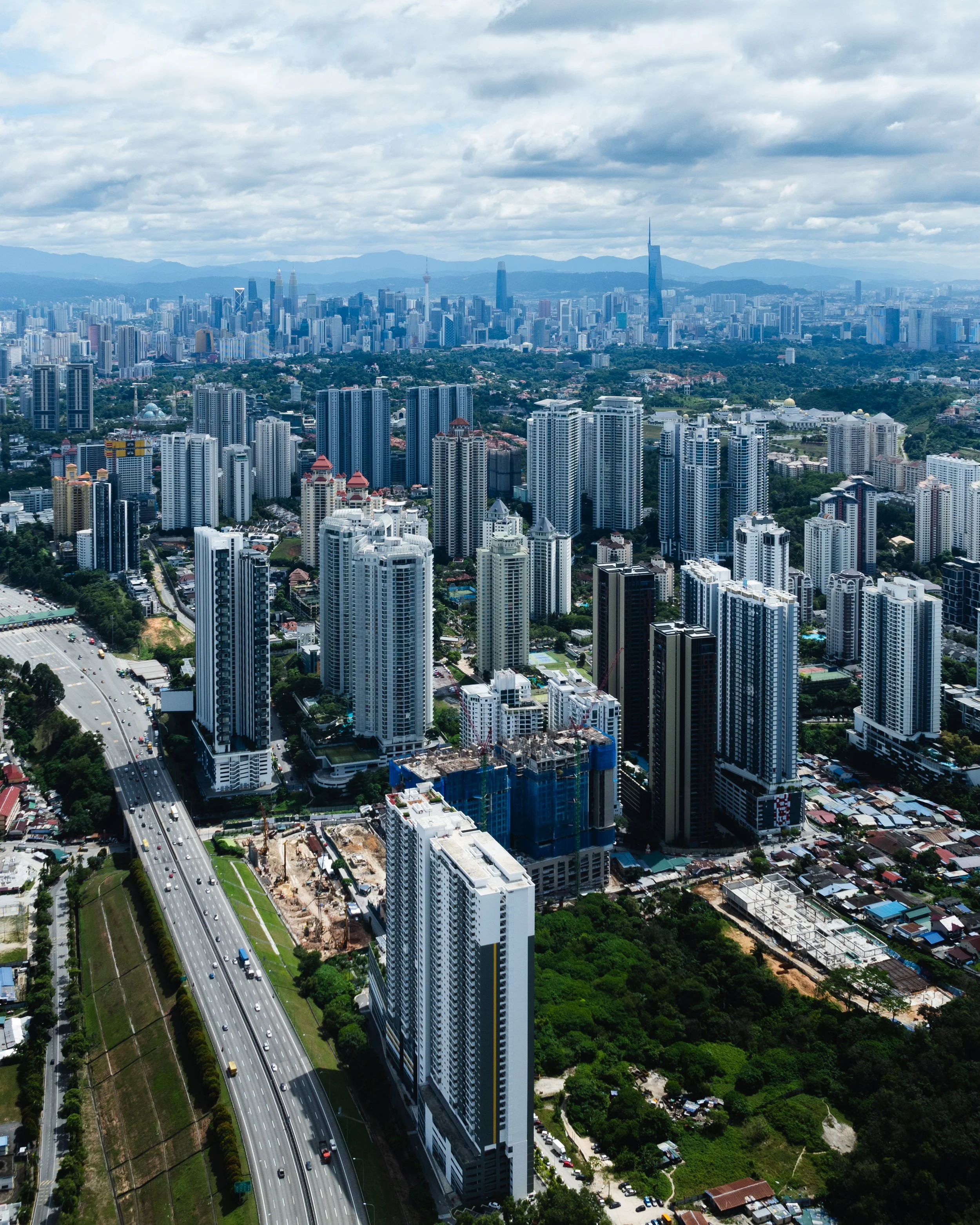 Kuala Lumpur, Malaysia — The city stretches endlessly in every direction, Merdeka 118 piercing the skyline in the distance. A highway cuts through the foreground. KL as it actually is — vast, layered and constantly building.