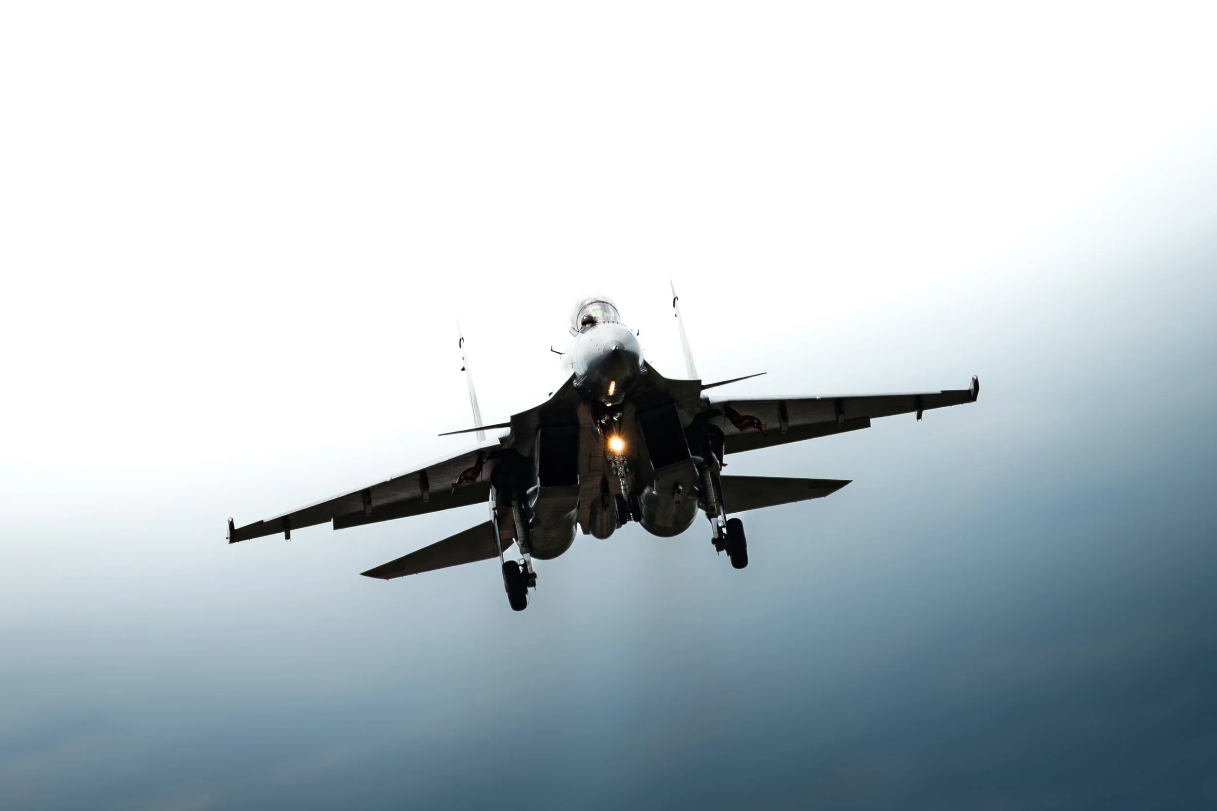 A modern fighter jet aircraft flying in the sky, viewed from below.
