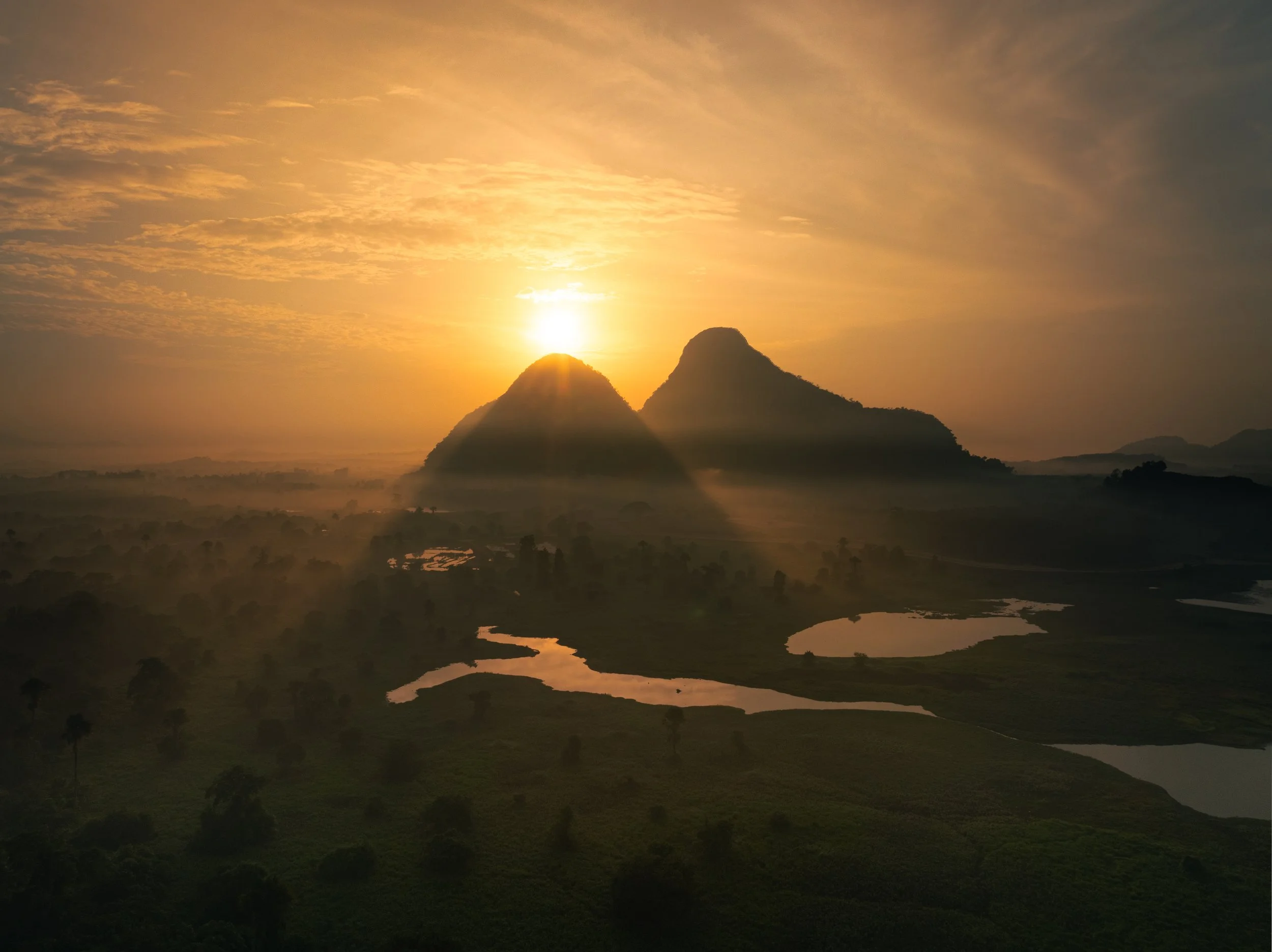 Perlis, Malaysia — The sun rises between two limestone peaks as mist rolls through the valley below, river channels catching the first light of the day. A landscape that reveals itself slowly, and only to those who arrive early enough.