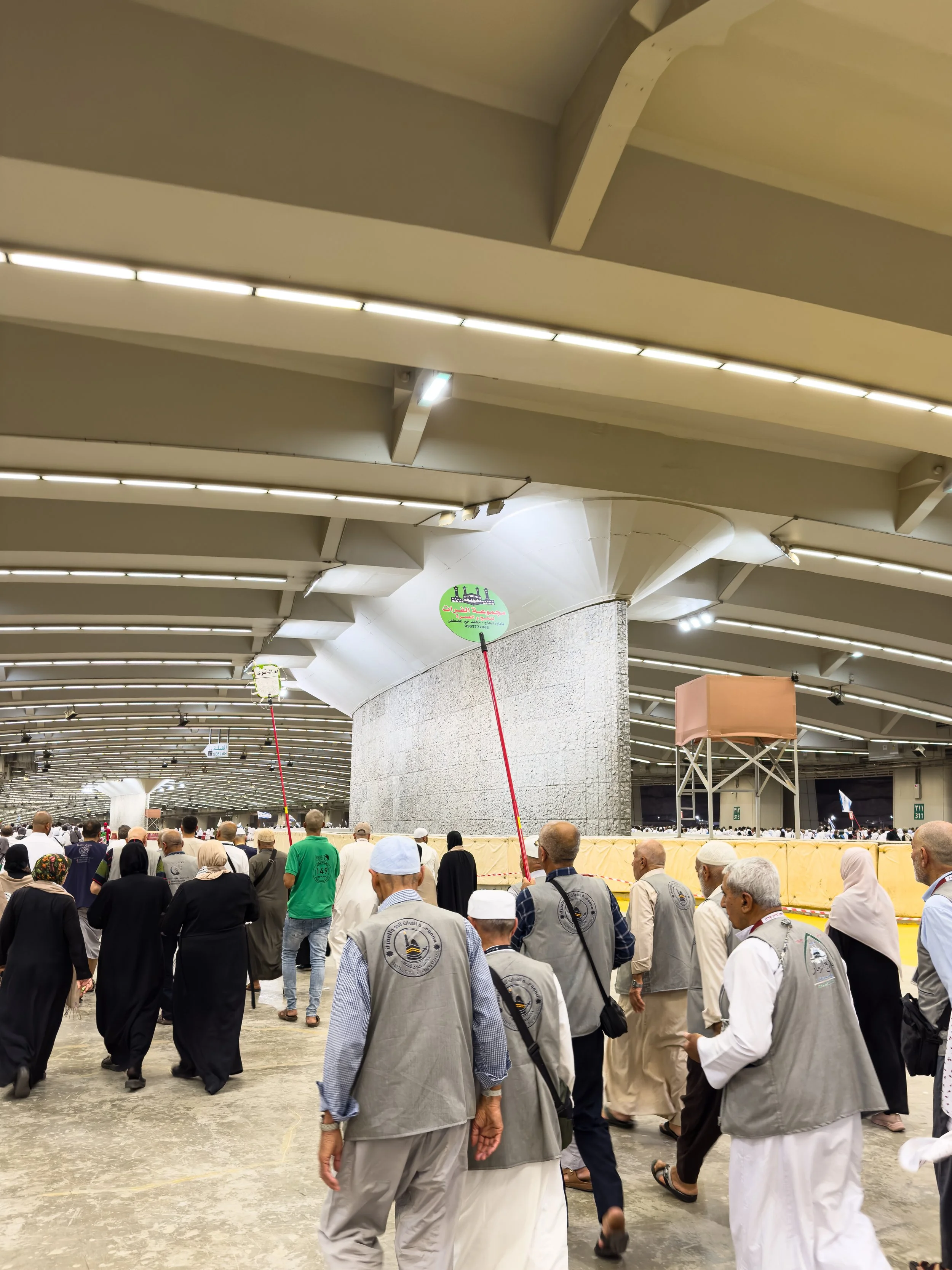 Jamarat Bridge, Mina, Saudi Arabia — Pilgrims converge on the Jamarat complex to perform the throwing of pebbles — one of Hajj's most ancient rituals. The crowd moves with purpose. Everyone holding exactly what's needed, nothing more.