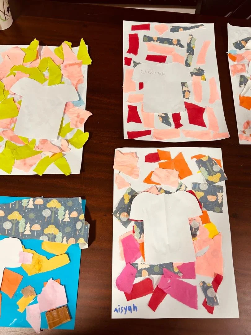 Colorful paper collages on a table, featuring torn paper shapes and cutouts of shirts.