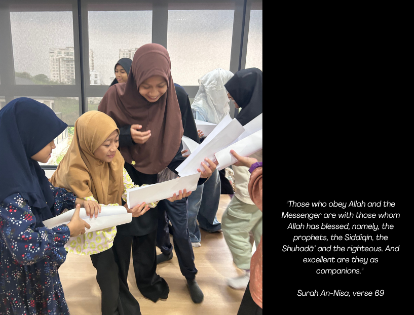 A group of women and children are inside a room with large glass windows, smiling and holding rolled-up papers, engaged in a joyful activity.