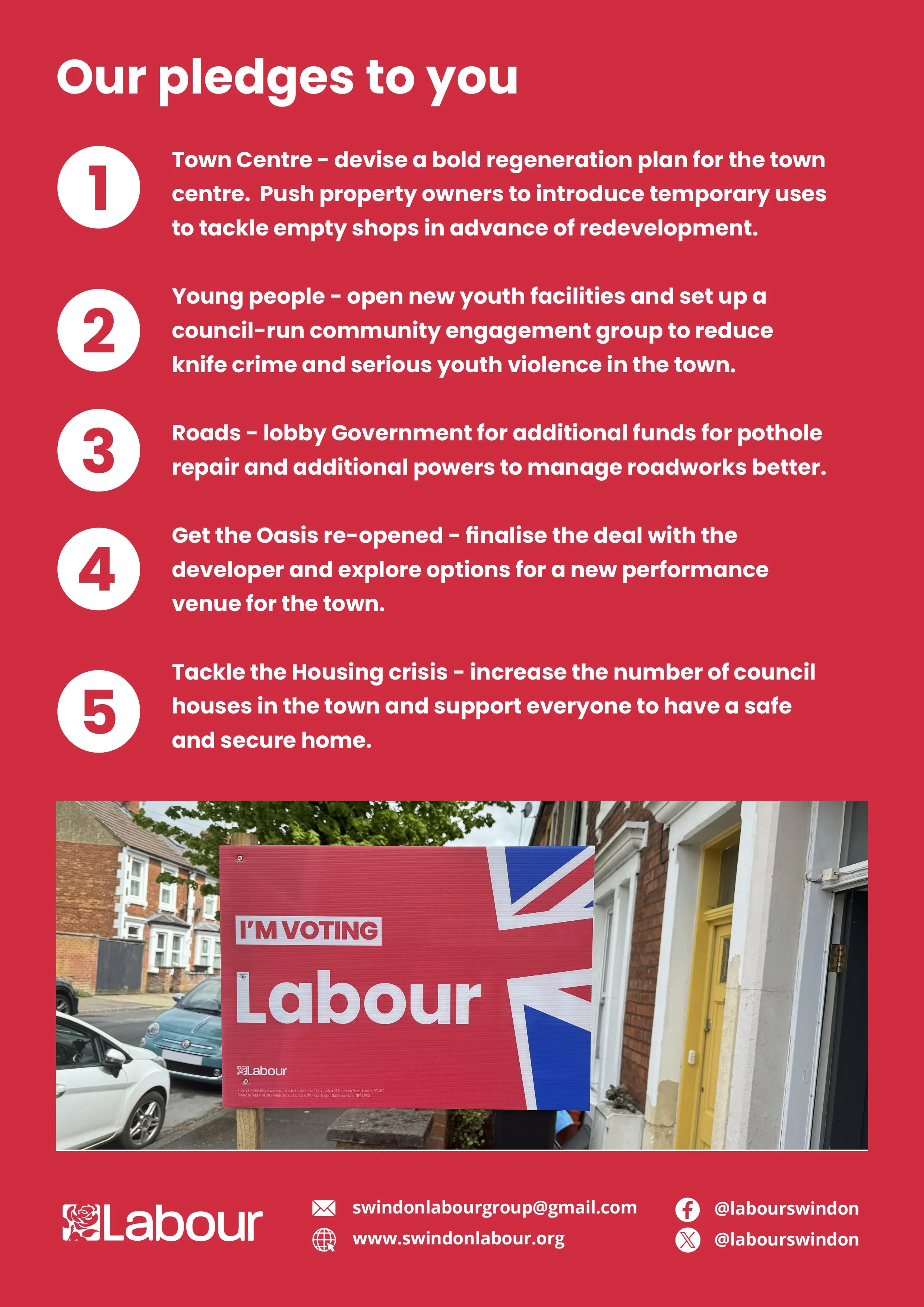 A red political campaign poster for Labour party with a Union Jack design, displaying the text 'I'M VOTING Labour' and contact details including an email, website, and social media handles, placed on a sidewalk with parked cars and residential buildi
