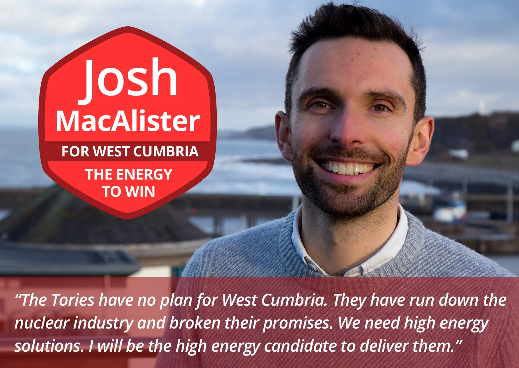 Portrait of a smiling young man with short dark hair and a beard, standing outdoors near the coast with a blurred background of overcast sky, water, and landscape. A red political campaign sign overlay reads: 'josh MacAlister FOR WEST CUMBRIA THE ENE